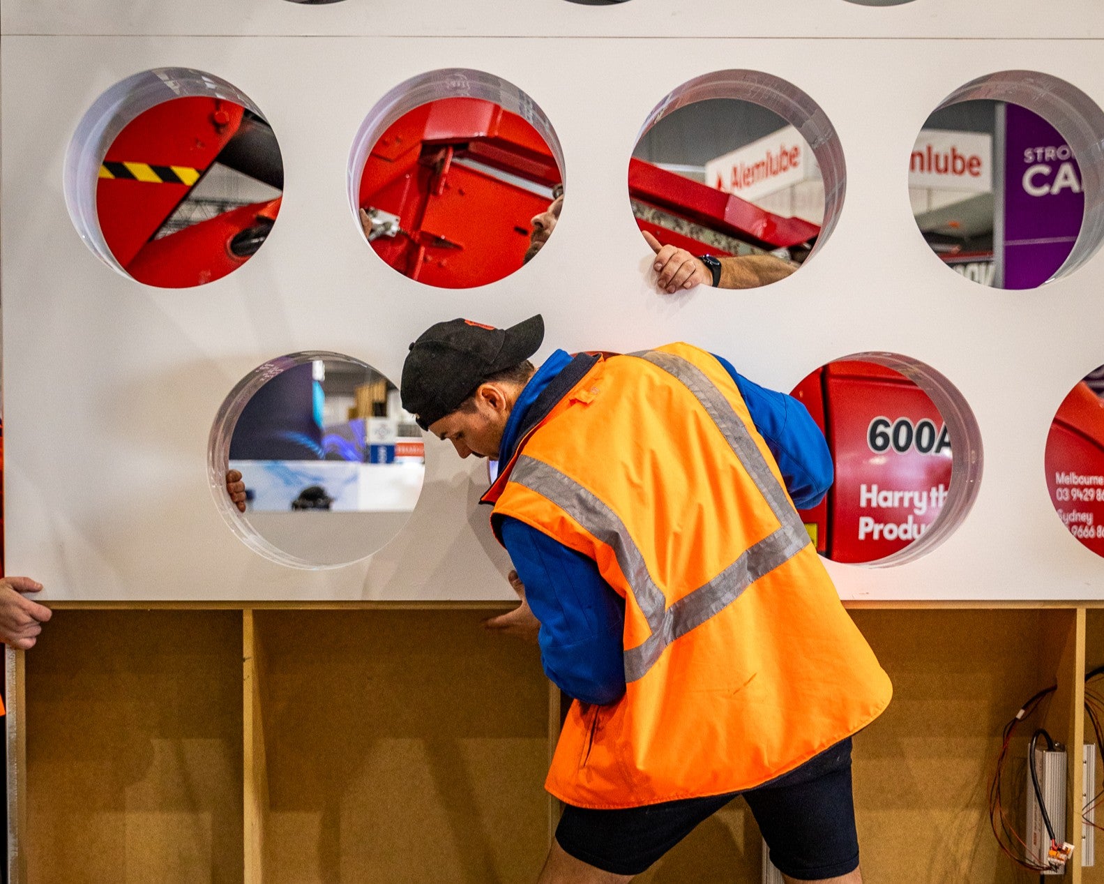Person in safety gear building a display of circular panels for an expo stand