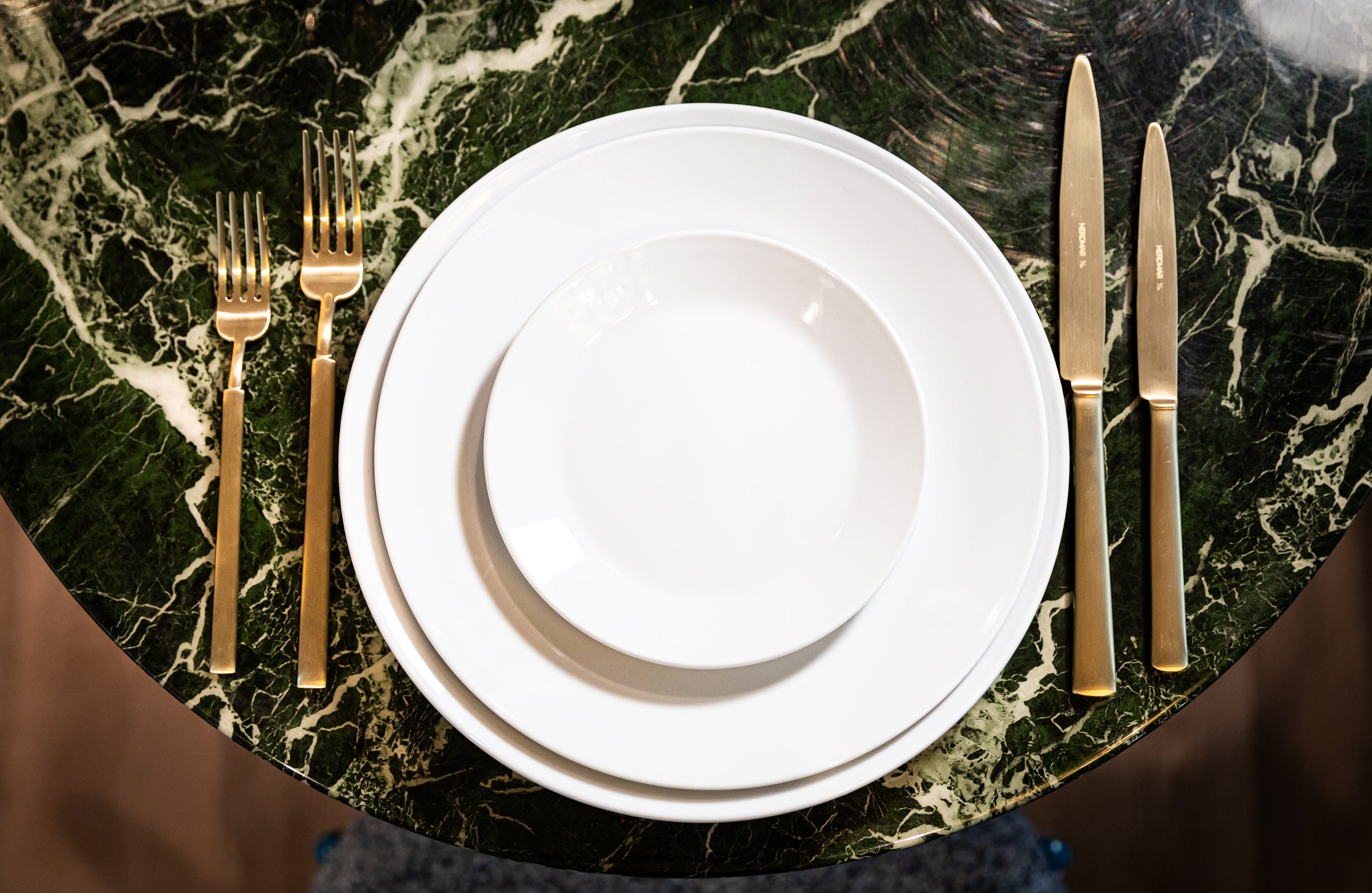 White plates with gold cutlery on a marble surface