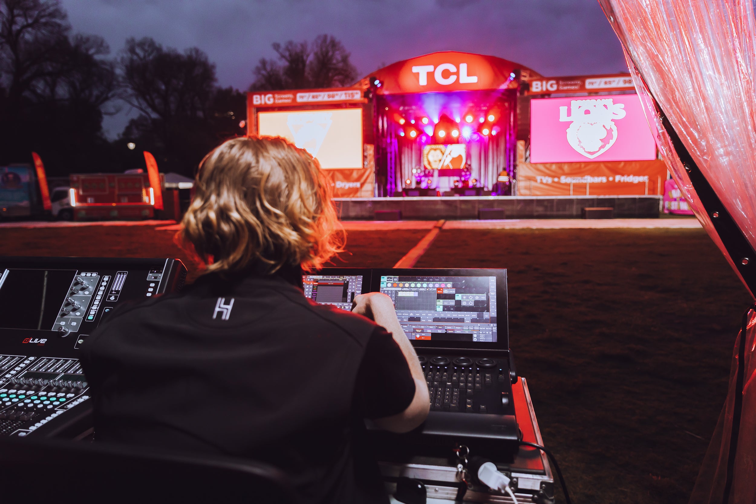 Person operating audio equipment at a concert with TCL branding on stage