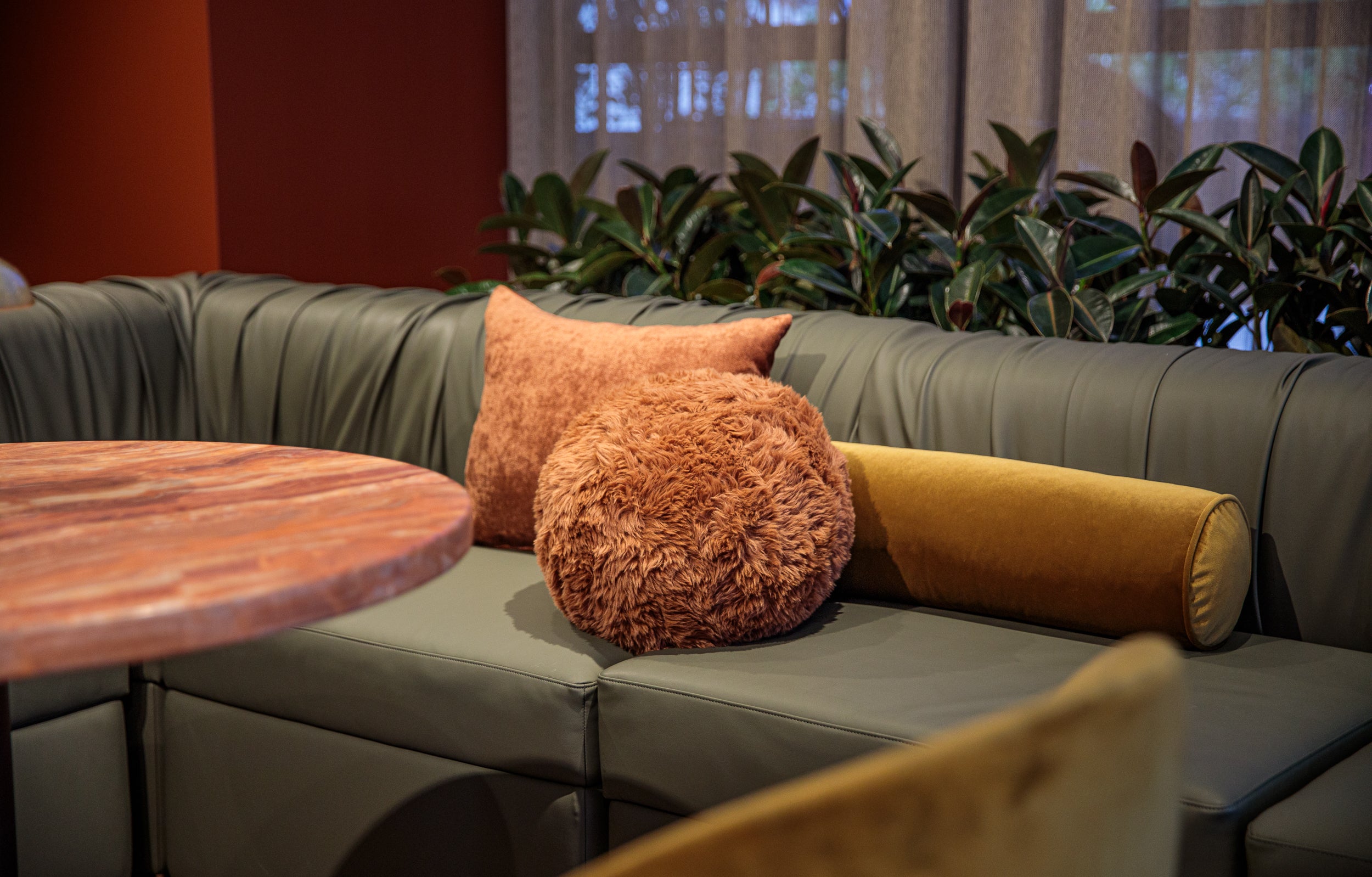 Green Rocco sofa with orange and yellow cushions in our Melbourne Showroom