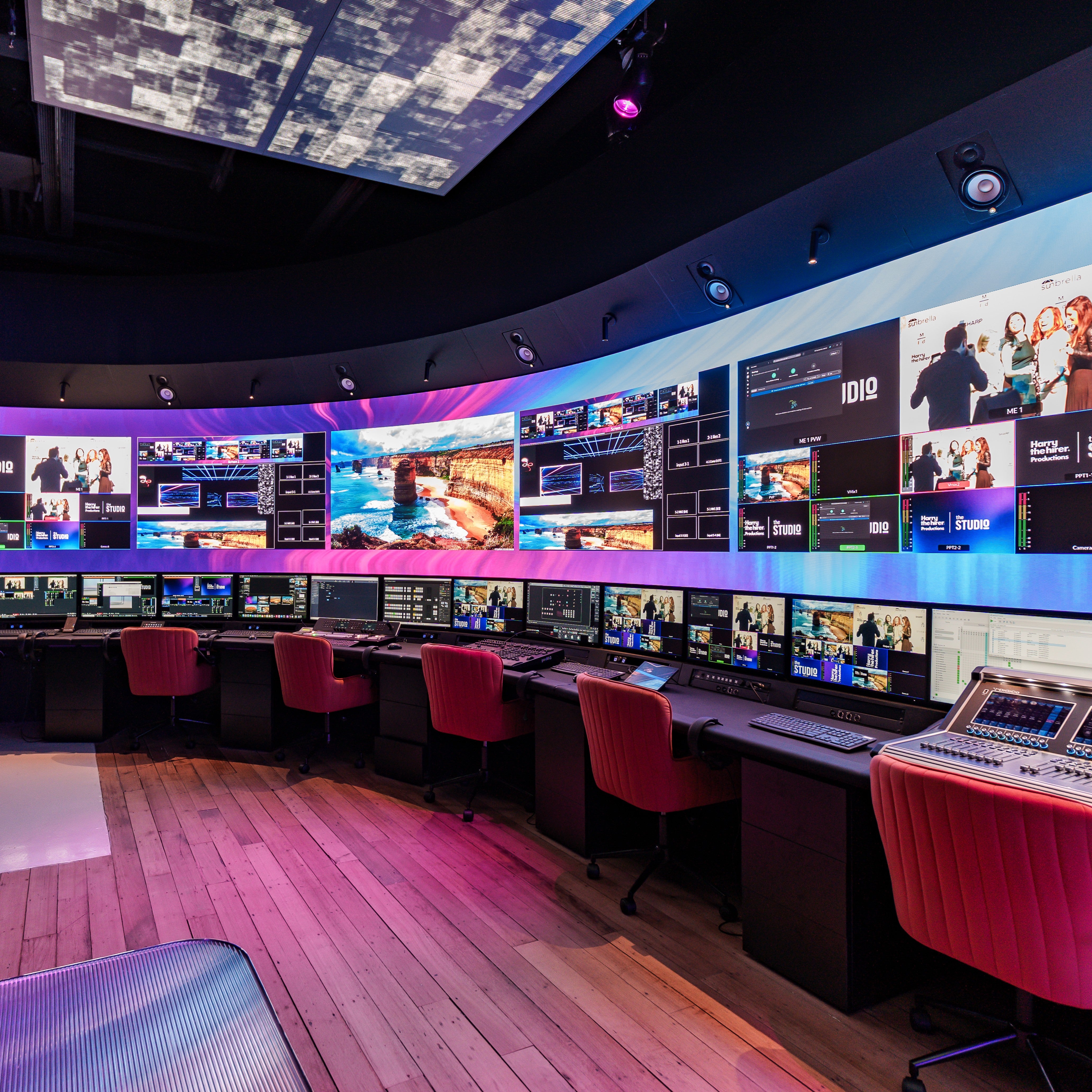 Control room with multiple monitors displaying various scenes, red chairs, and a curved wall in our Studio in Melbourne