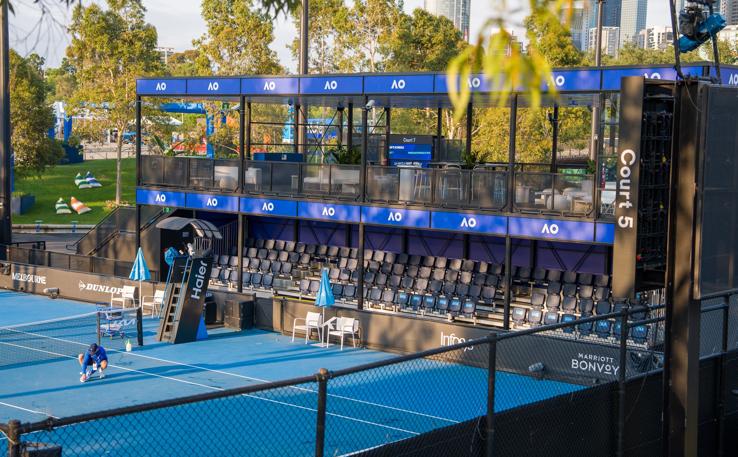 Tennis court with blue surface and spectator stands, featuring the Australian Open logo.