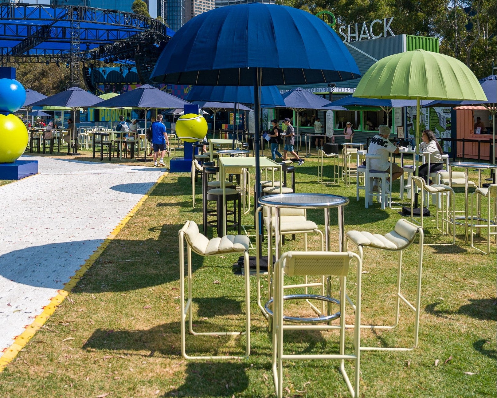Outdoor event with tables, chairs, and colorful umbrellas at Australian Open