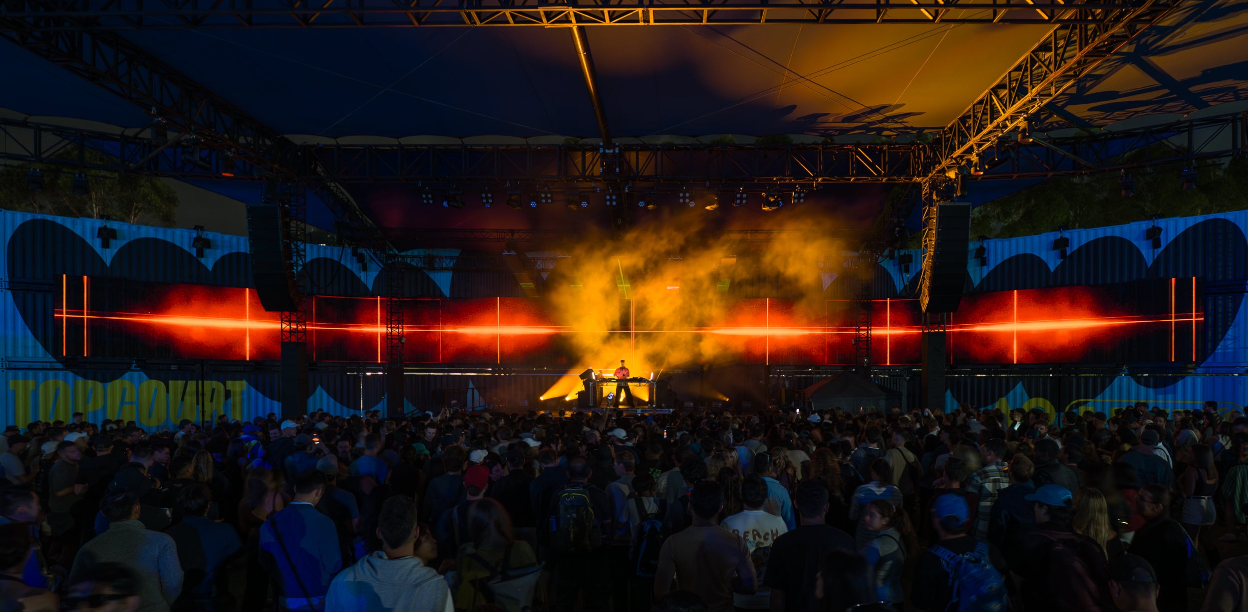 DJ set on stage with a crowd and colorful lights at a music festival. Black Widow screen behind DJ projecting an orange display. Shot at Australian Open.