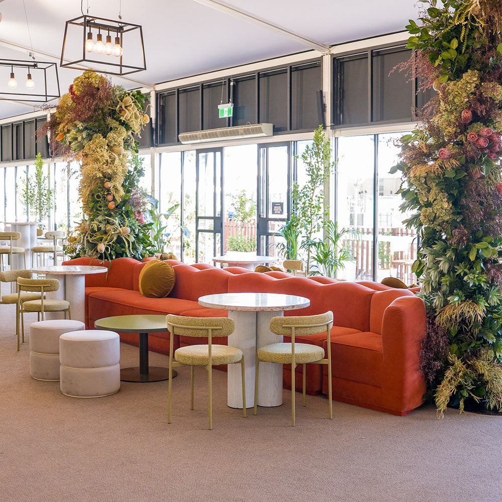 Modern interior with orange sofa, round tables, and decorative plants.