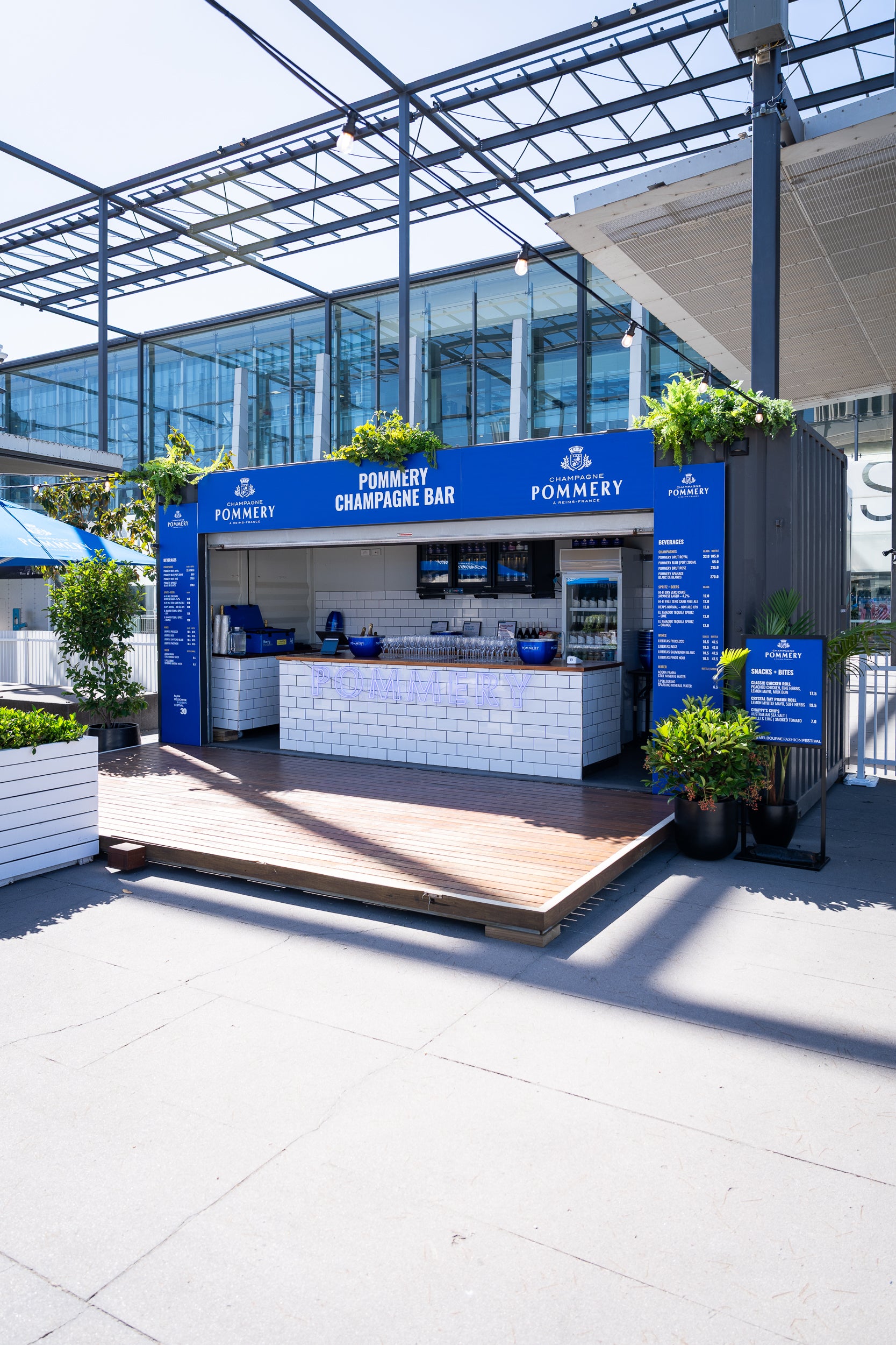 Pommery champagne bar stand with blue and white design in an outdoor setting.