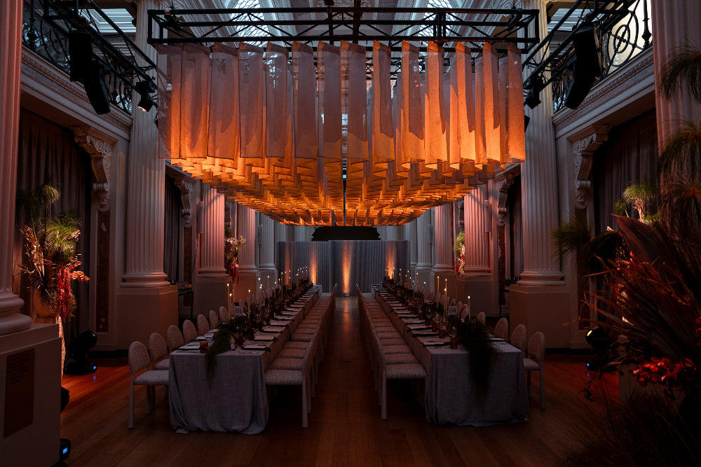 Dramatic interior setting with hanging fabric and long tables set for a formal event.