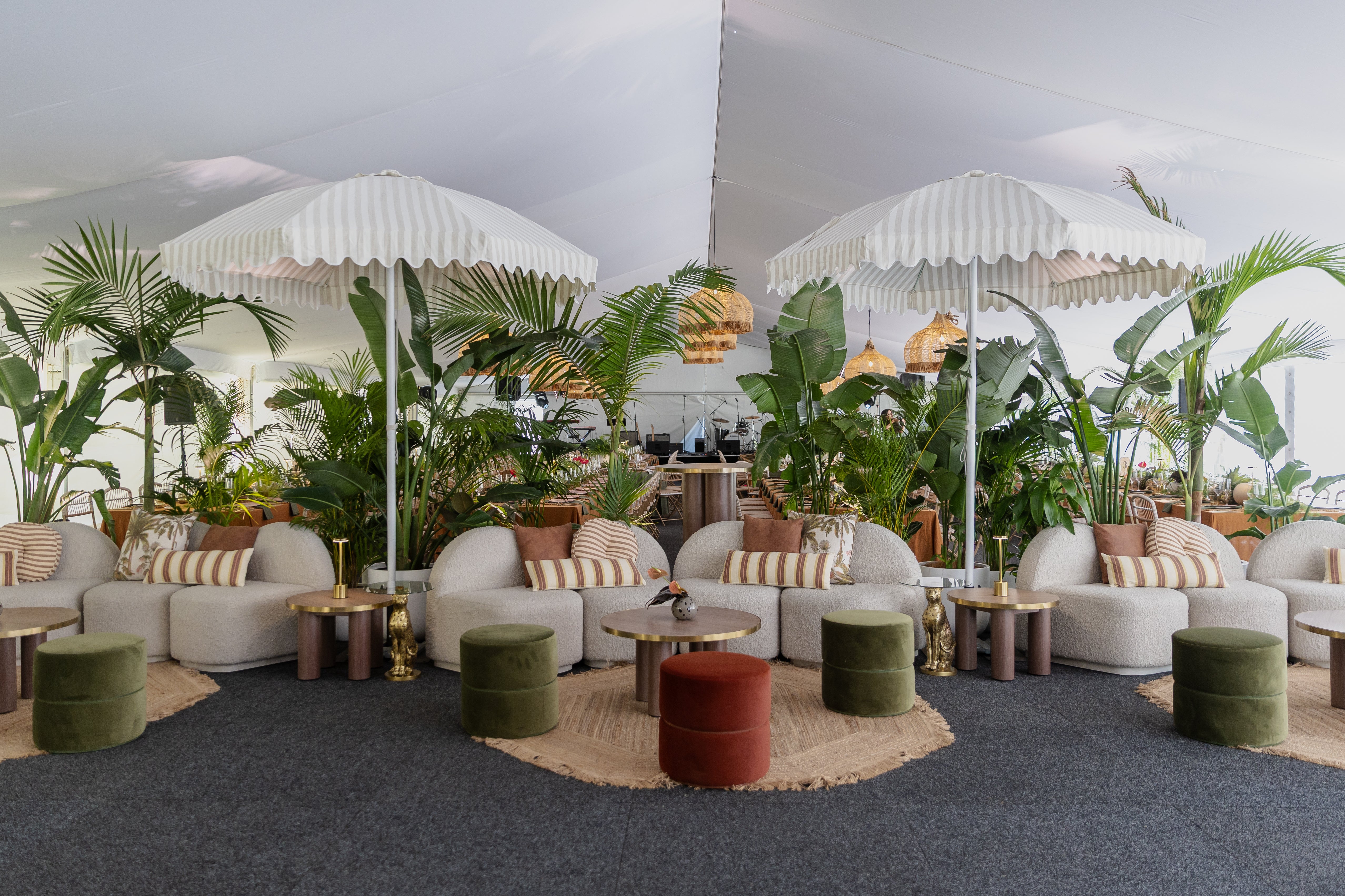 Birthday seating area with white furniture, green ottomans, and large umbrellas.