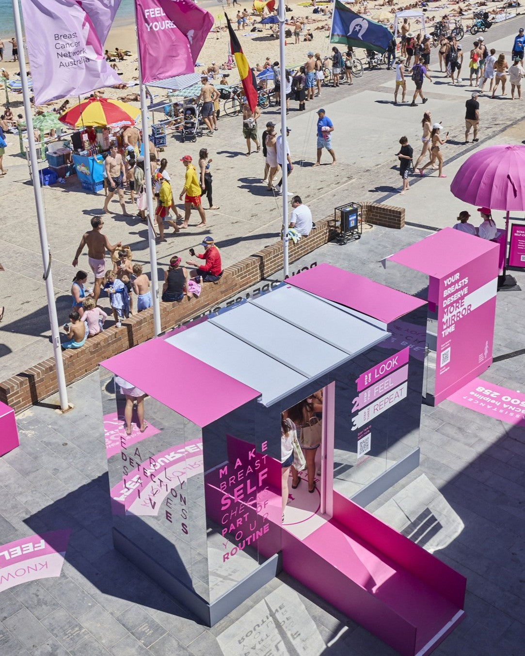 Pink and mirrored pop-up booth with people around on a sunny day for BCNA in Bondi
