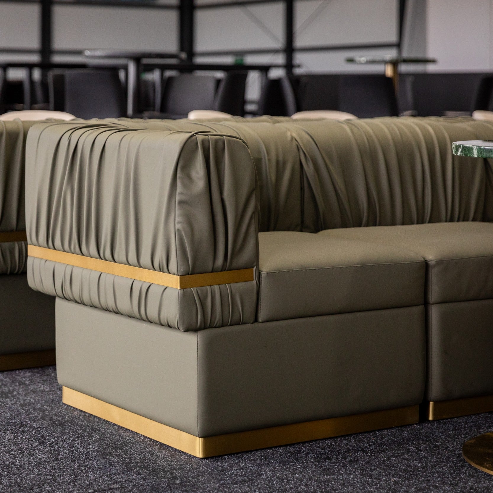 Green Rocco sofa with gold accents in a suite with tables and chairs at Melbourne Spring Racing Carnival