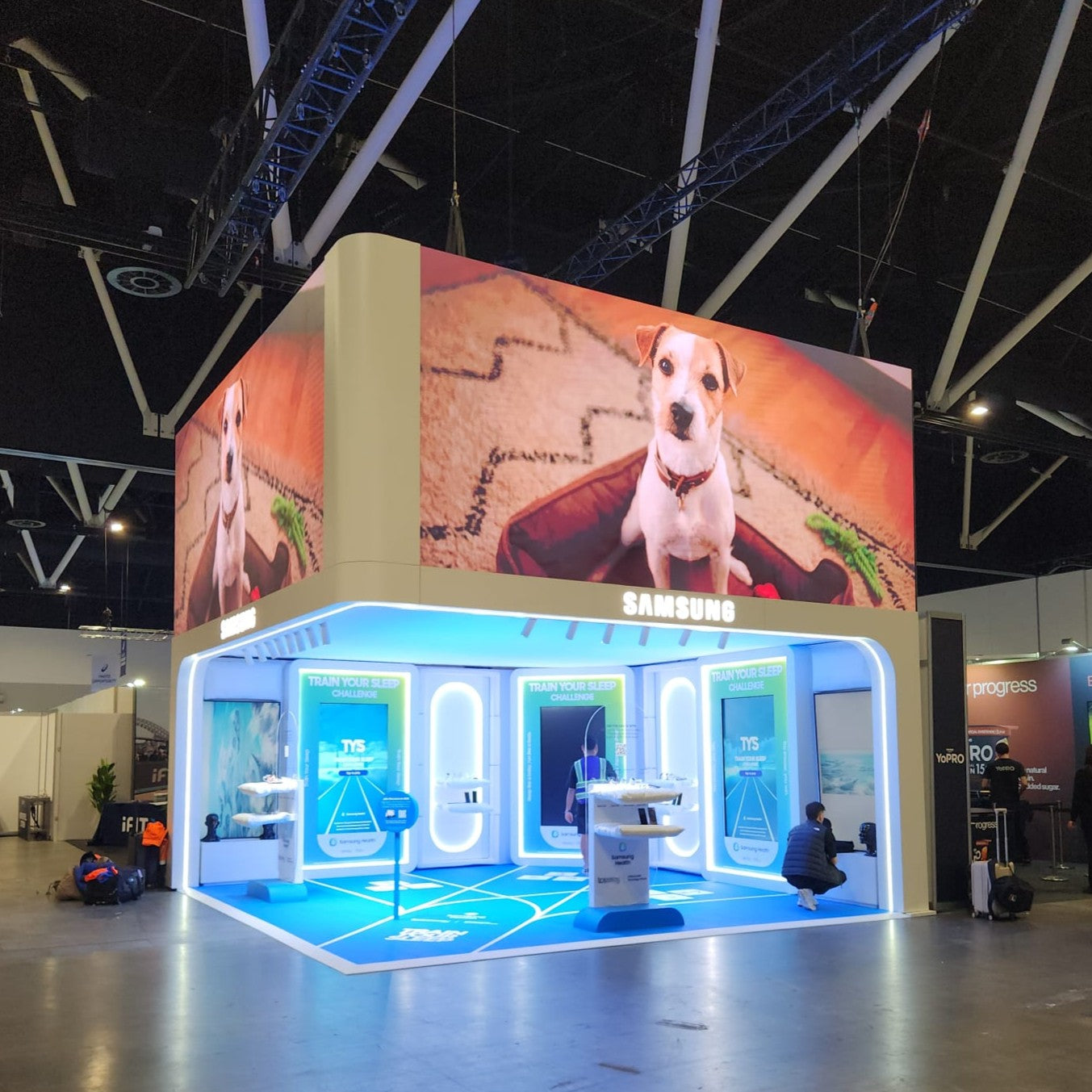 Samsung booth at a trade show with large screen displaying a dog and Samsung logo.
