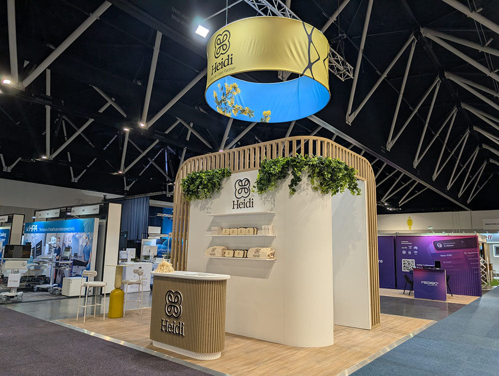 Heidi booth at a trade show with branding and decorative elements.