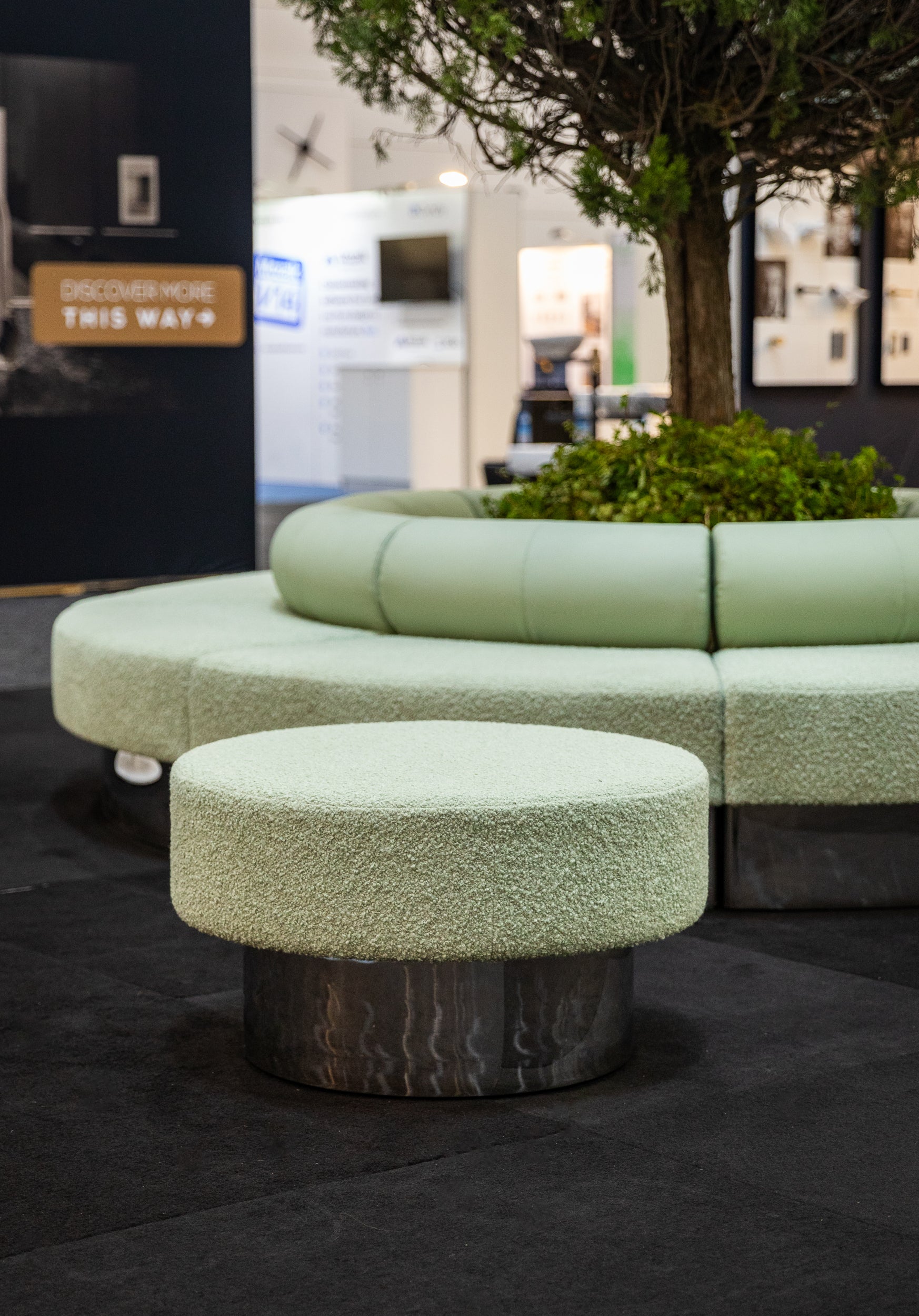 Green textured sofa and ottoman on a dark floor with blurred background