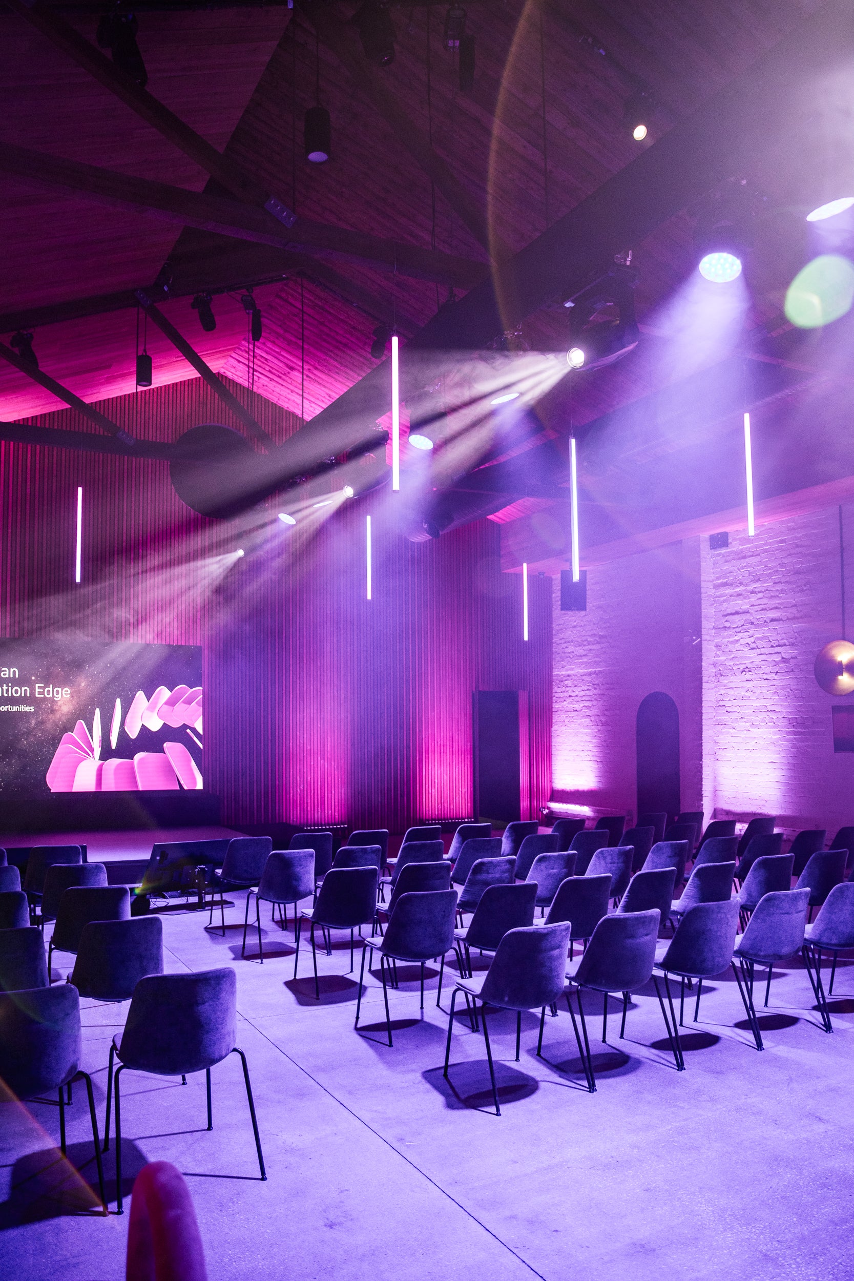Auditorium with purple lighting and rows of chairs facing a screen.