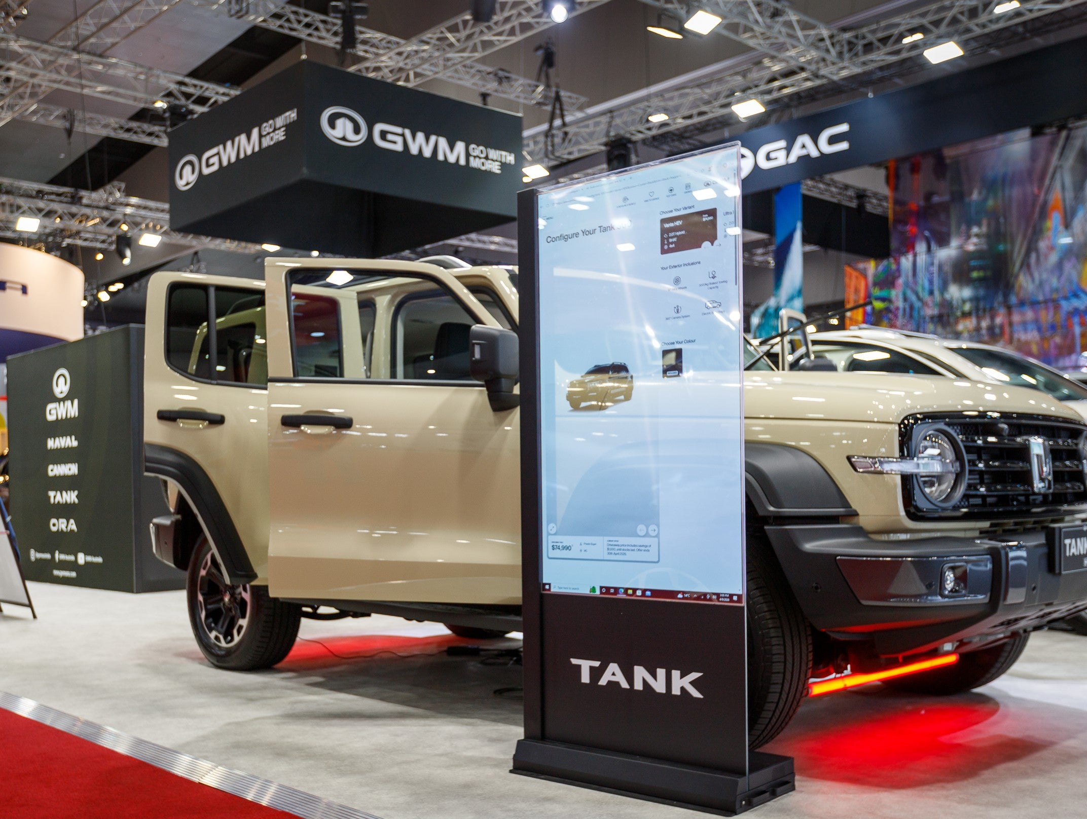 Beige GWM vehicle on display at a car show with digital display and 'GAC' branding.