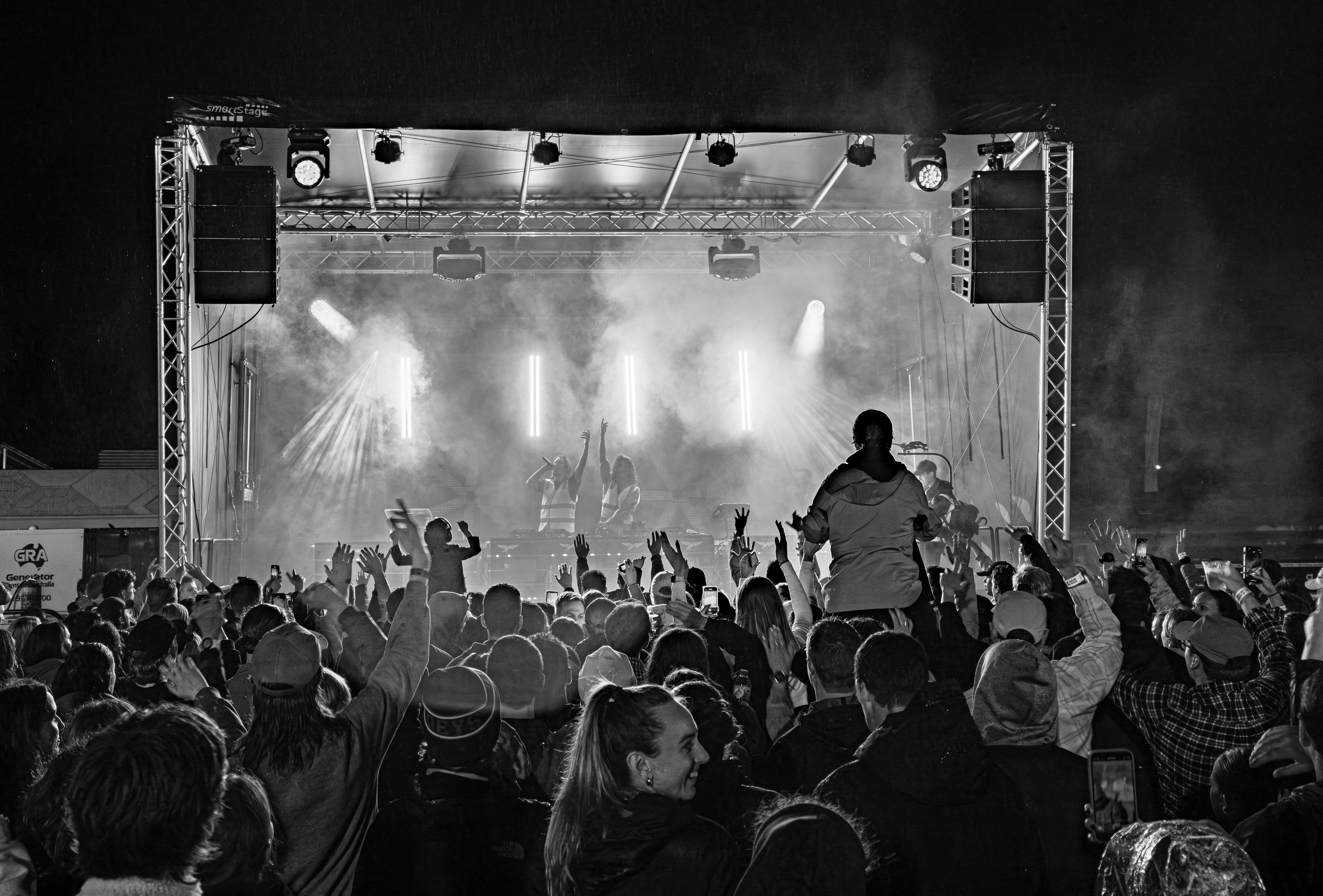People at a concert with a stage and lights in the background. Crowd infront of a HTH Productions-built stage