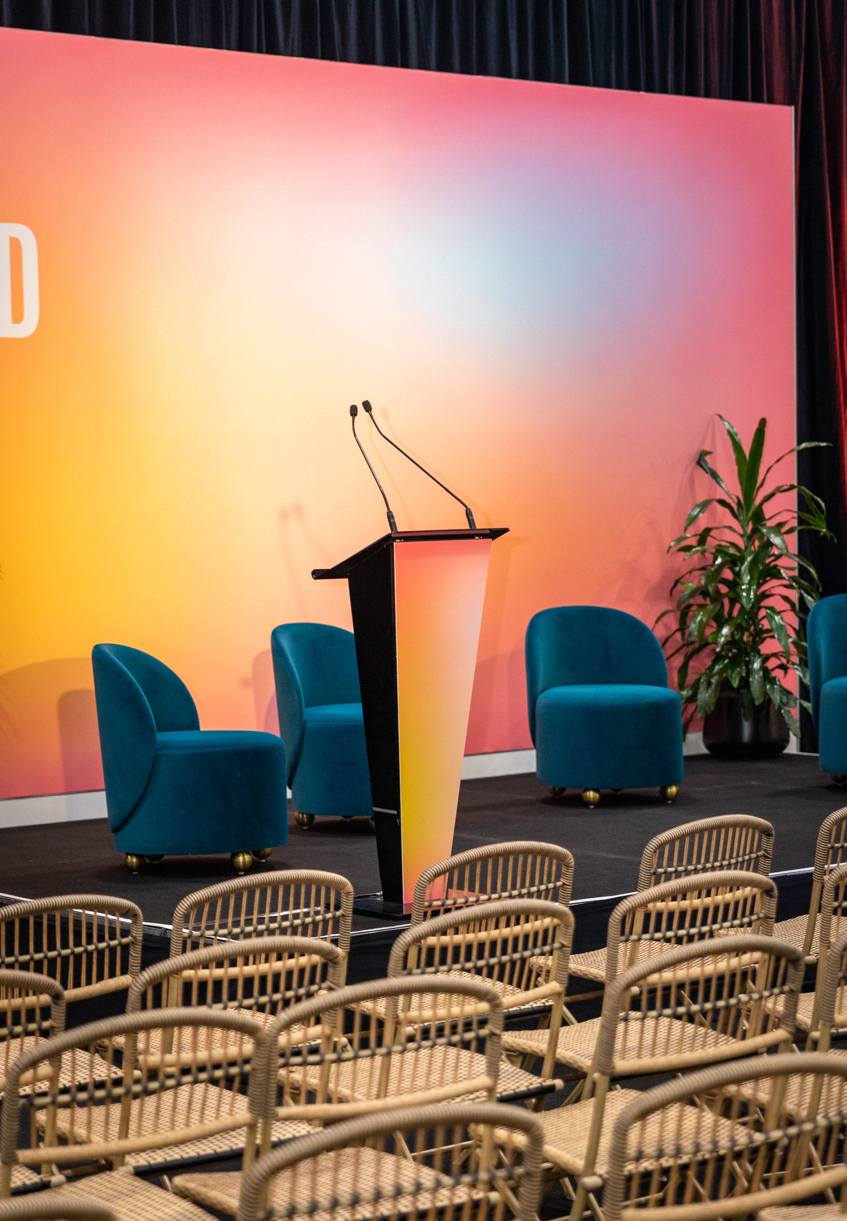 Conference room setup with blue chairs, a podium, and a colorful wall.