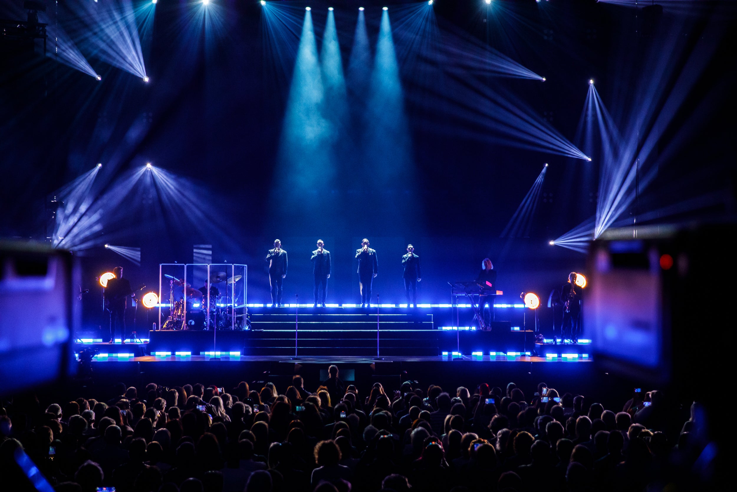 Stage with performers under blue lights during a concert