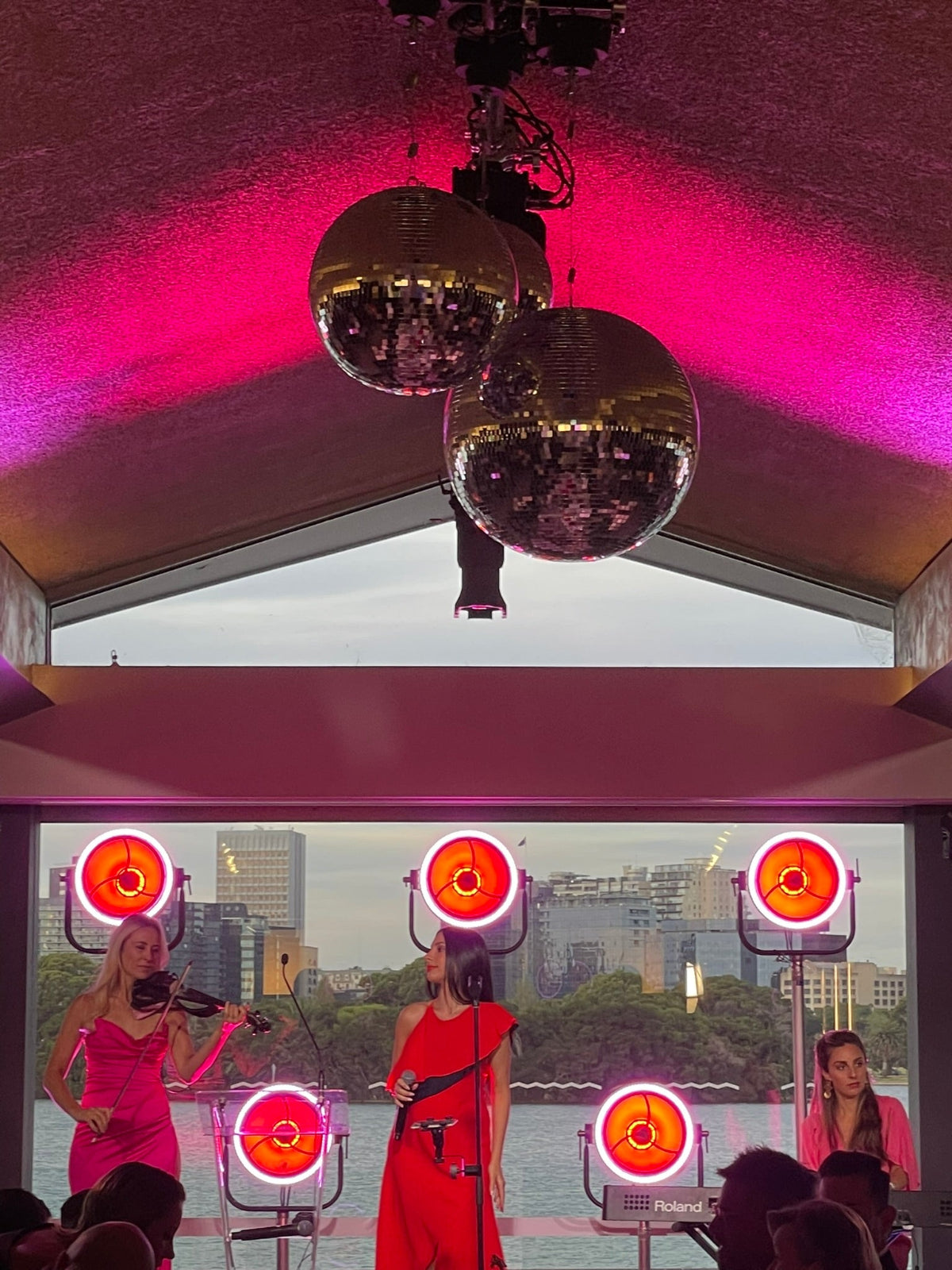 Discoballs hanging from a ceiling with a cityscape view through large windows.