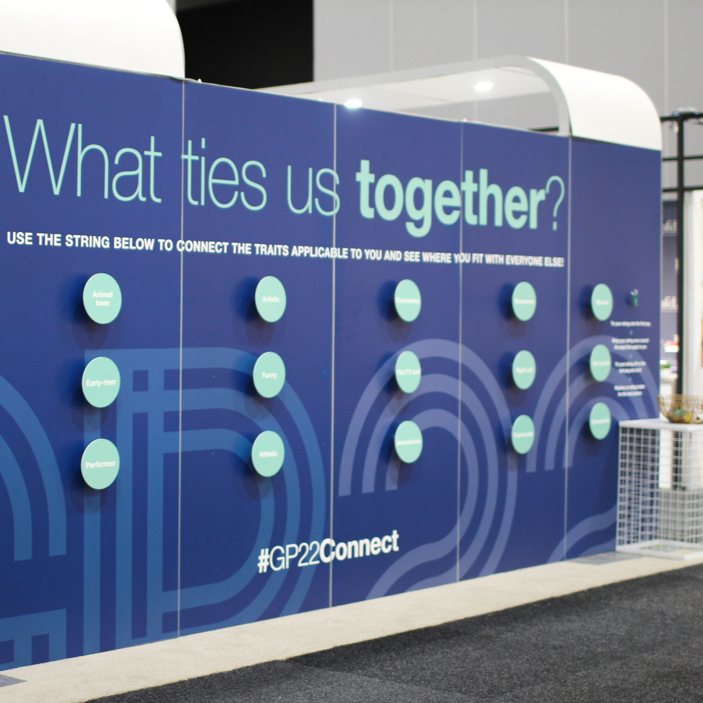 Blue interactive wall with green buttons and text asking 'What ties us together?' in an outdoor setting.