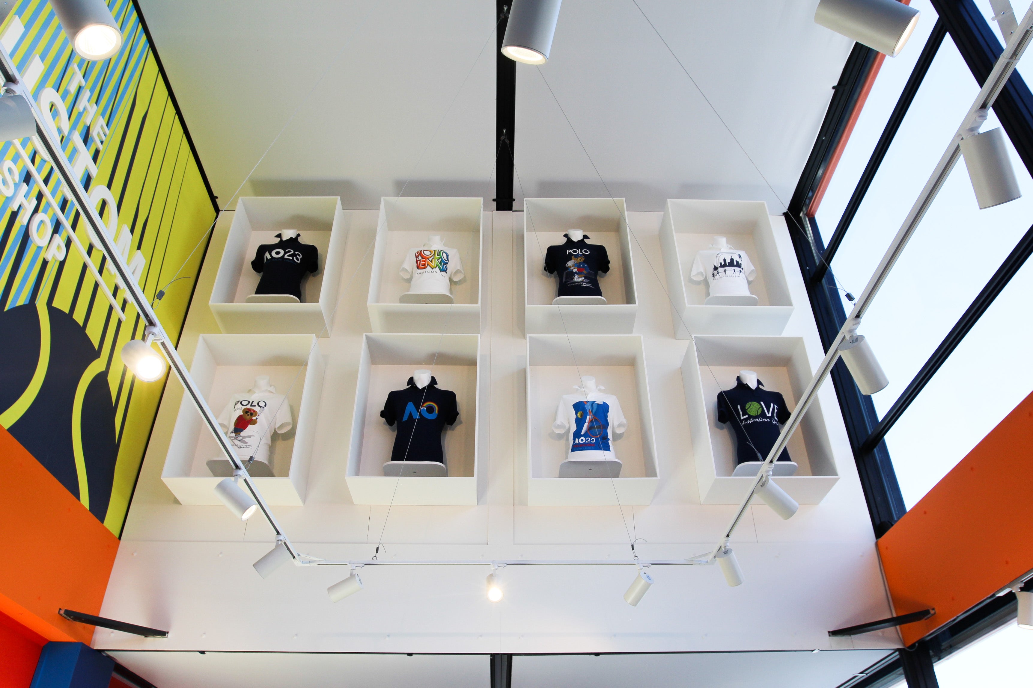 Display of t-shirts in a grid on a white shelf with colorful background