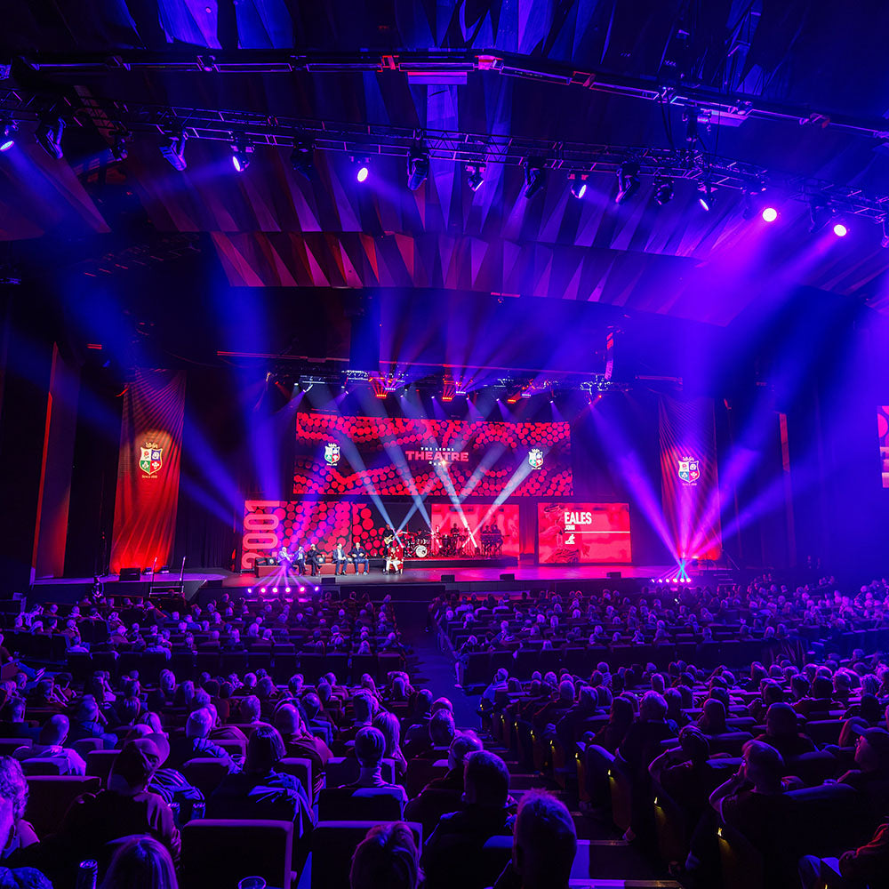 Concert hall with a stage and audience under colorful lights