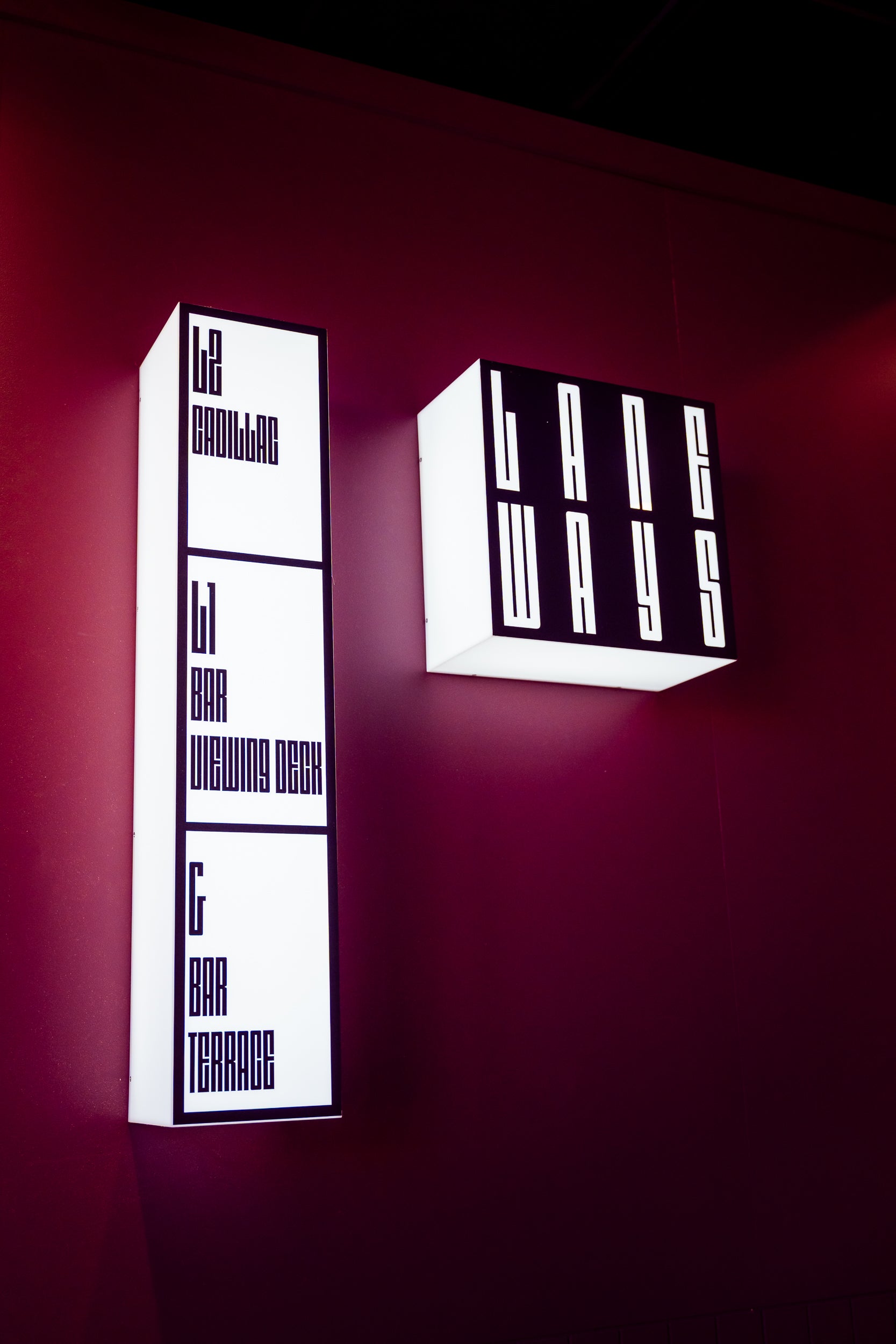 Two modern wall lights on a dark red wall