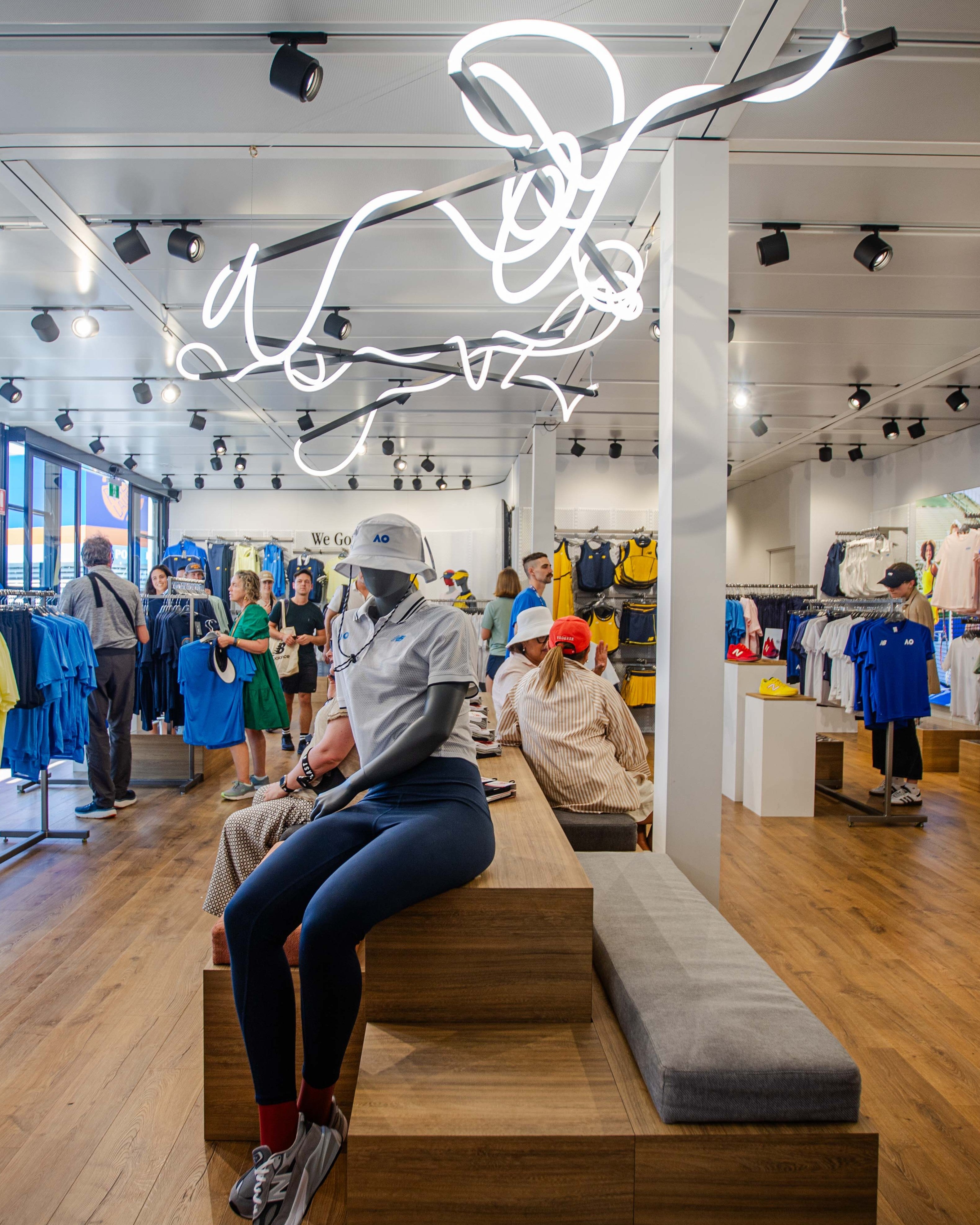 Interior of a modern store with neon sign and people sitting on benches with custom detailing in a marquee