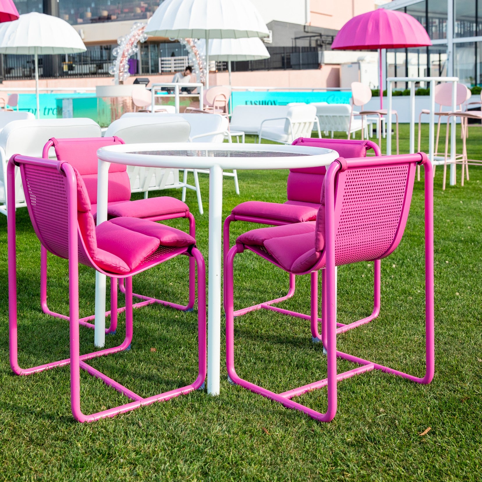 Pink Isla chairs and Helix table set on grass with umbrellas in the background. Onsite at Spring Racing Carnival.