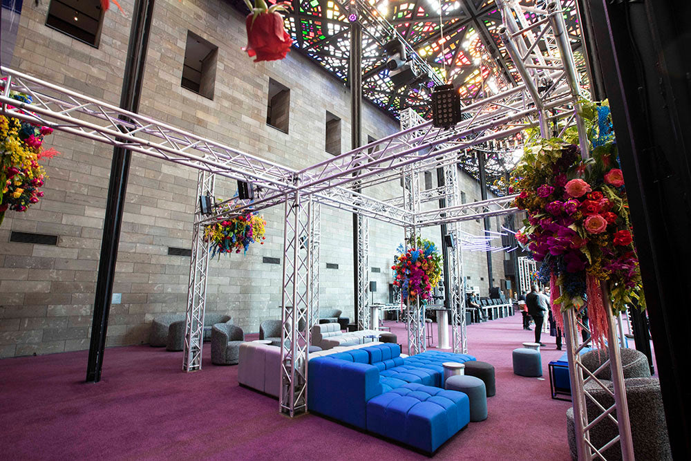 Decorative setup with floral arrangements and a blue sofa in an indoor setting.