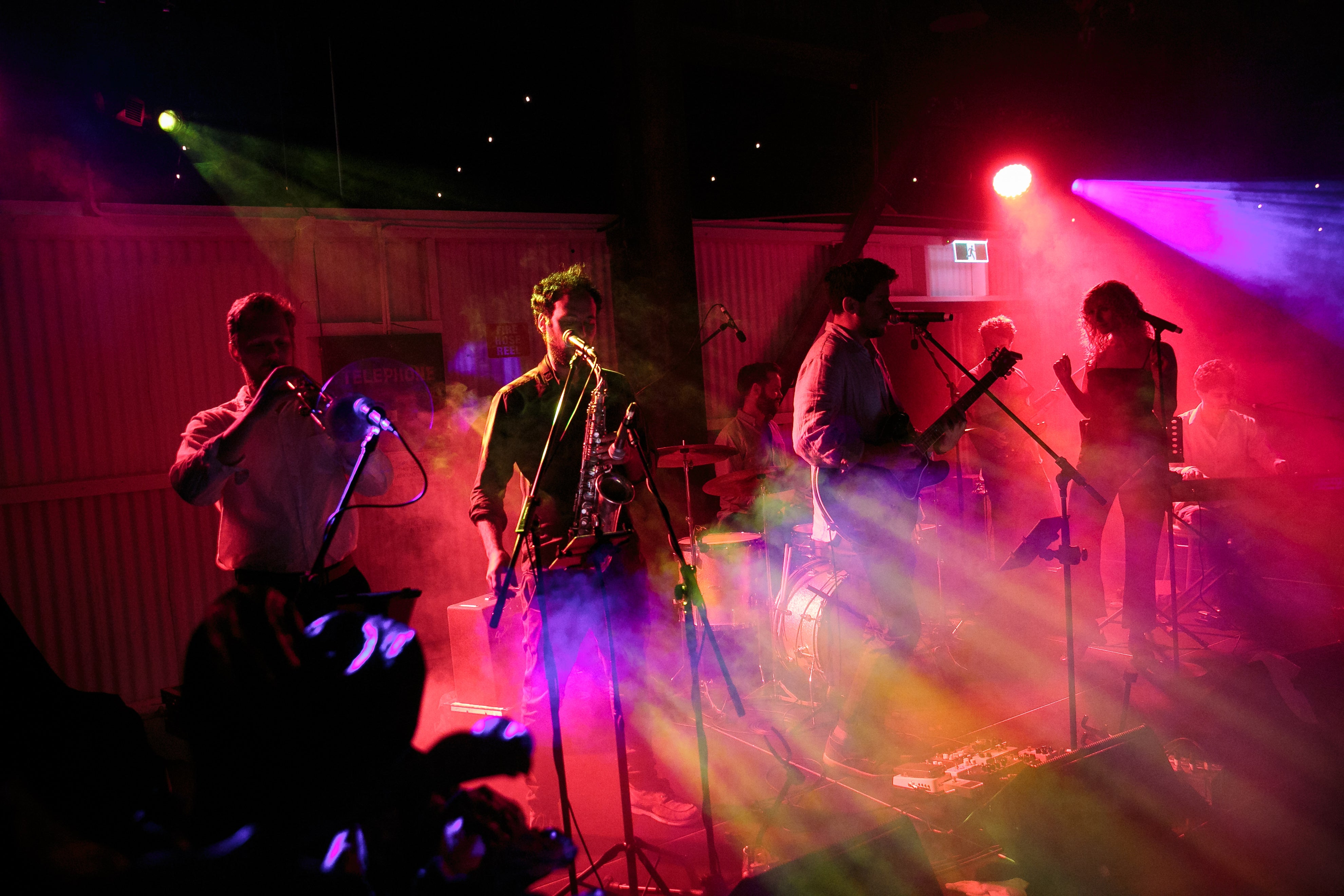 Band performing on stage with colorful lights and a dark background