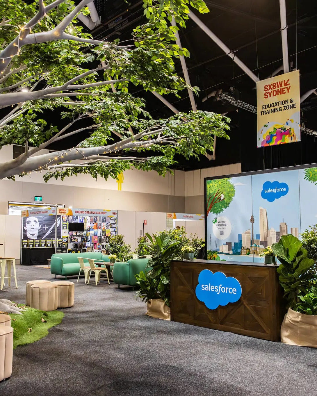 Salesforce booth at a convention center with greenery and digital display.
