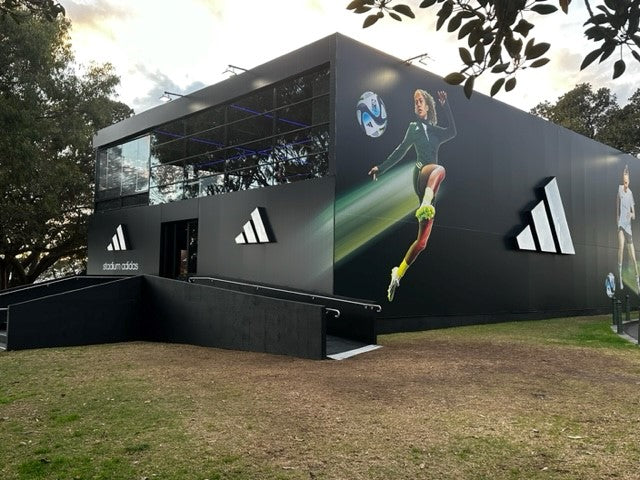 Adidas branded marquee with large windows and outdoor display of athletes running.