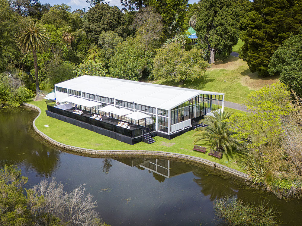 Alto Marquee and black base, surrounded by greenery and a pond. Taken at Melbourne Botanical Garden