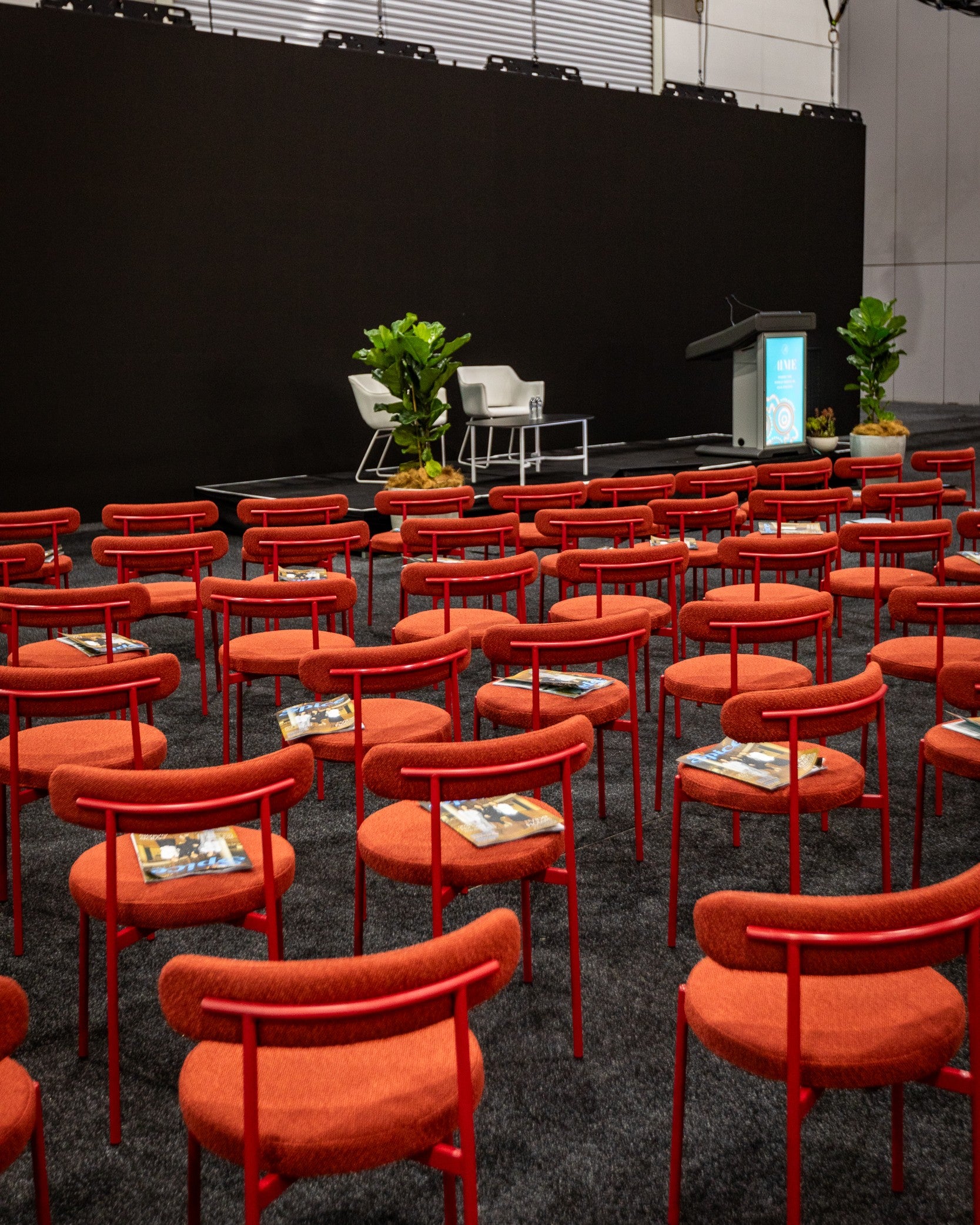 Red chairs arranged in rows with a black backdrop in a conference room setting.