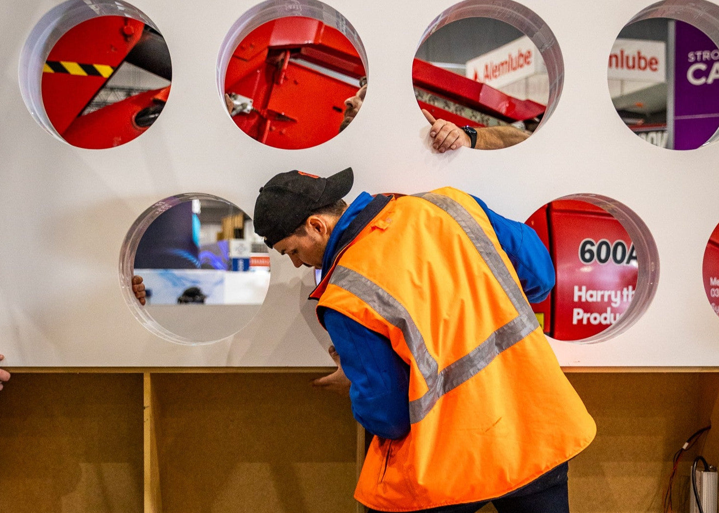 Person in safety gear building a display of circular panels for an expo stand