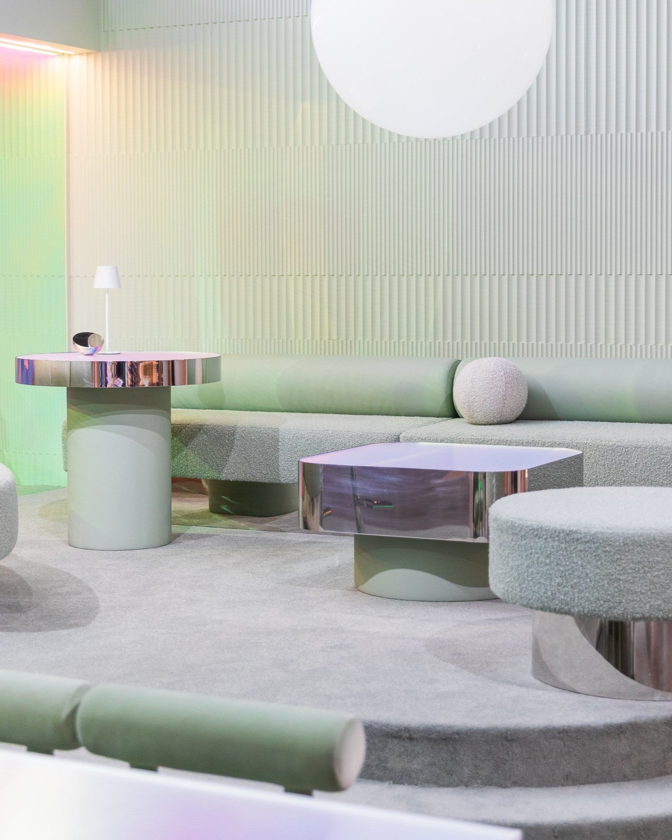 Modern living room with pastel green sofa, chrome coffee table, and textured wall.