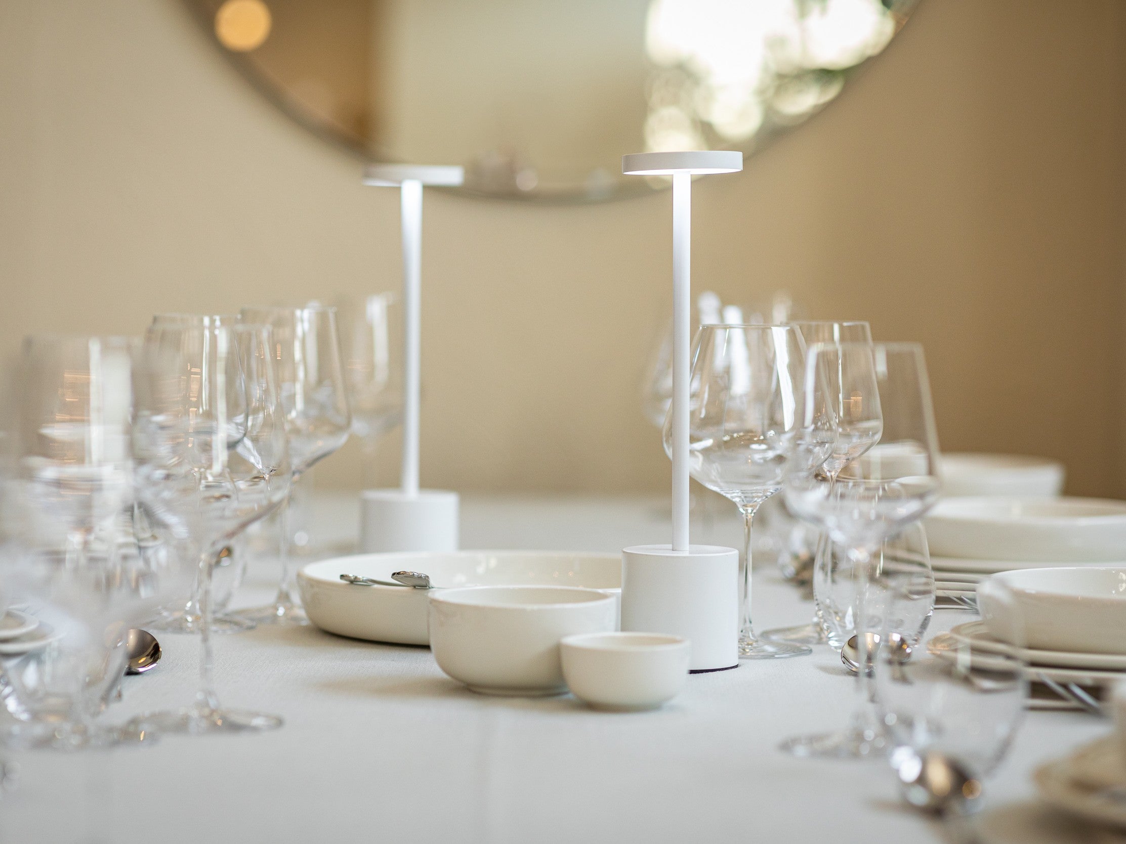 Dining table set with glasses, bowls, and cutlery on a neutral background