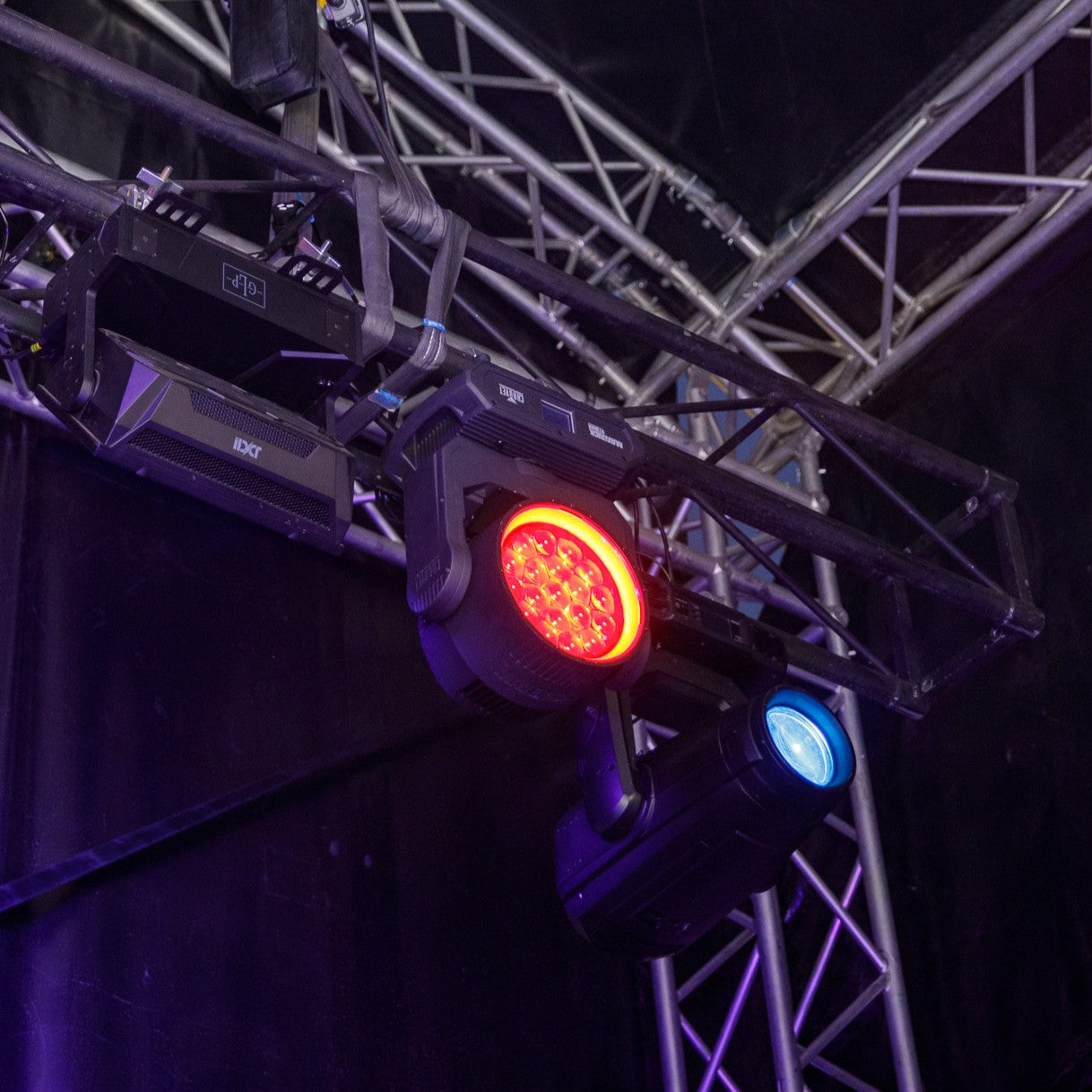 Stage lighting equipment and rigging with red and blue lights on a dark background