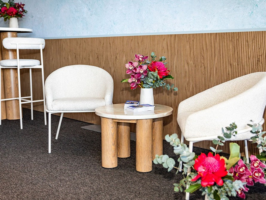 Modern interior with white chairs, wooden tables, and floral arrangements.