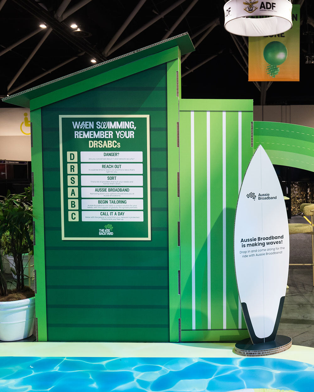 Green beach hut signage with a surfboard and Aussie Broadband branding