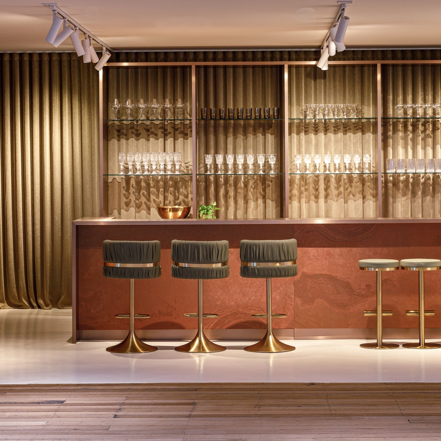 Moody bar setting with rich burgundy tones, gold bar stools and draped fabric wall treatments. Shot in our Melbourne Showroom