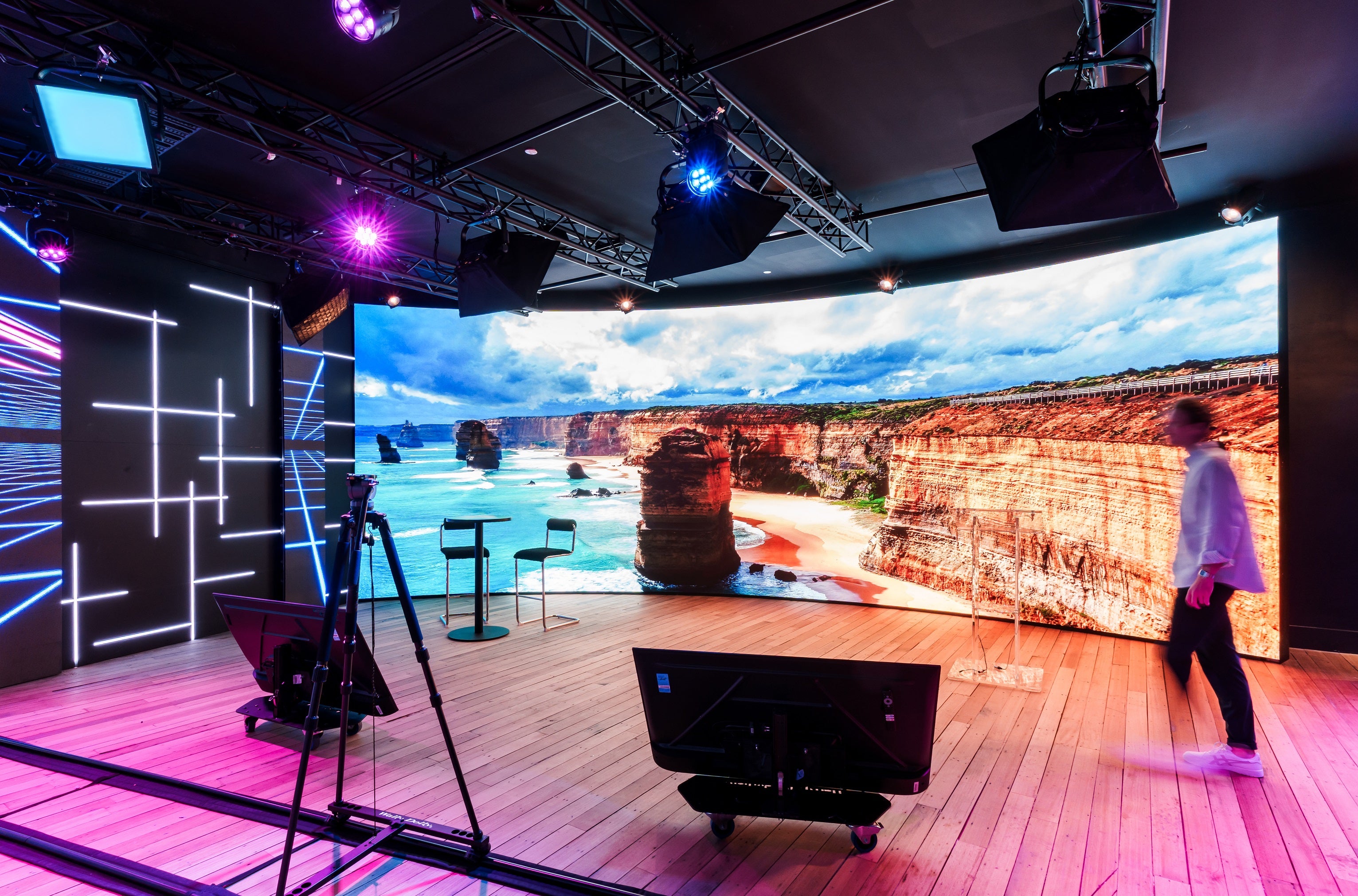 A large curved screen displaying a scenic landscape, surrounded by stylish furniture and decor.