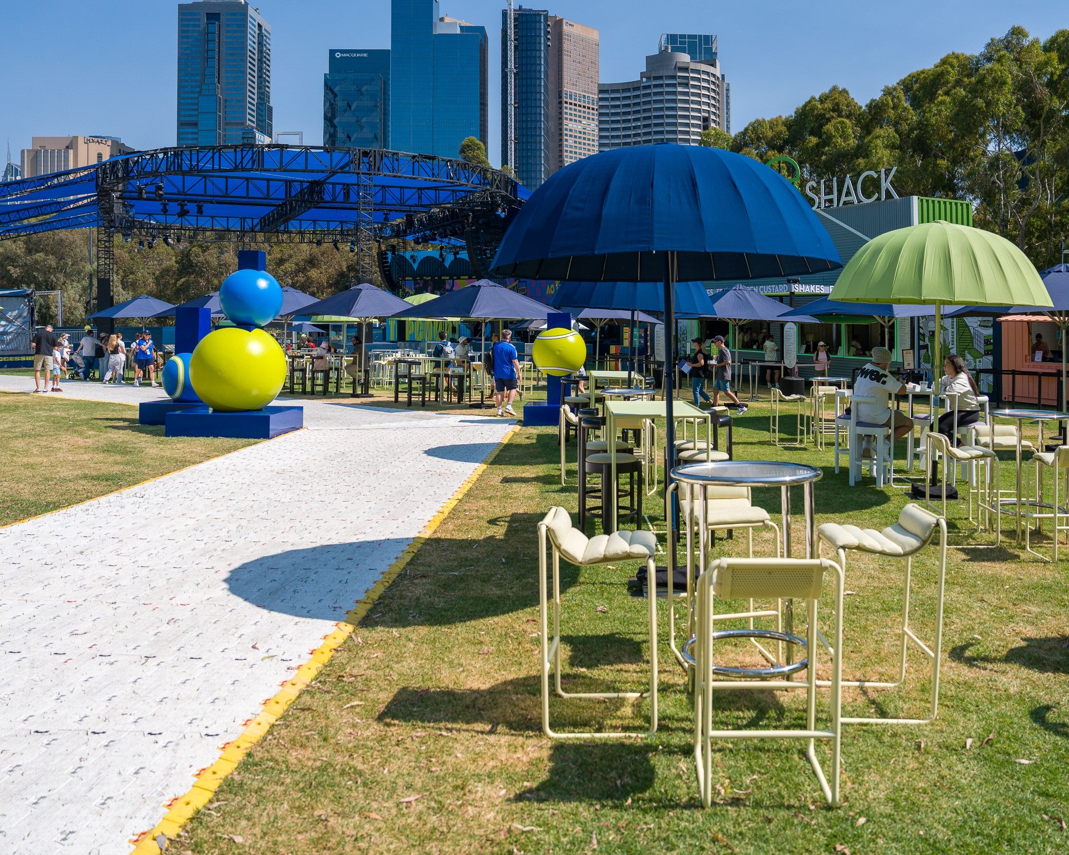 Outdoor event with tables, chairs, and colorful umbrellas at Australian Open
