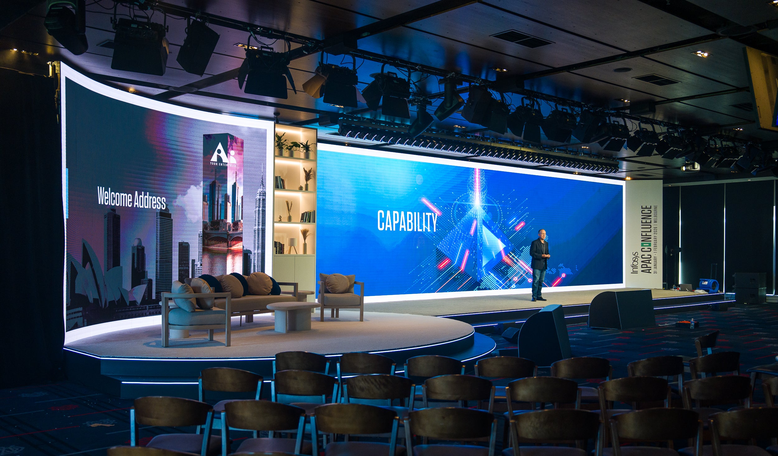 Modern conference room with a large screen displaying 'Capability' and a speaker on stage.