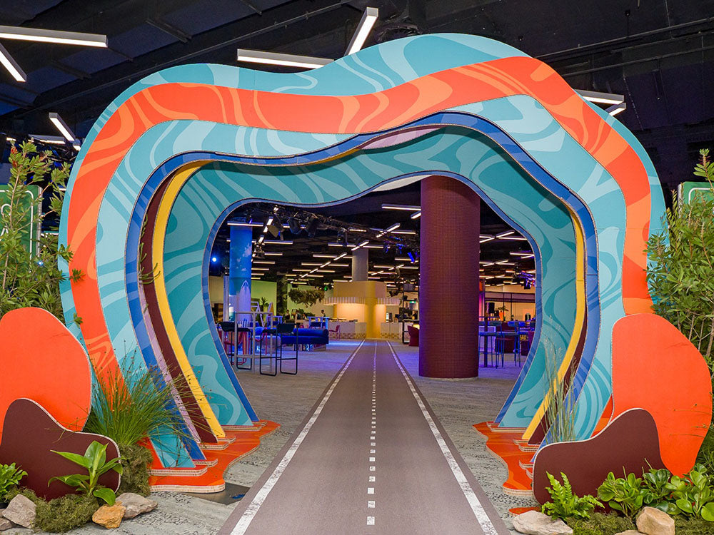 Colorful archway installation in a expo hall with plants and a pathway.