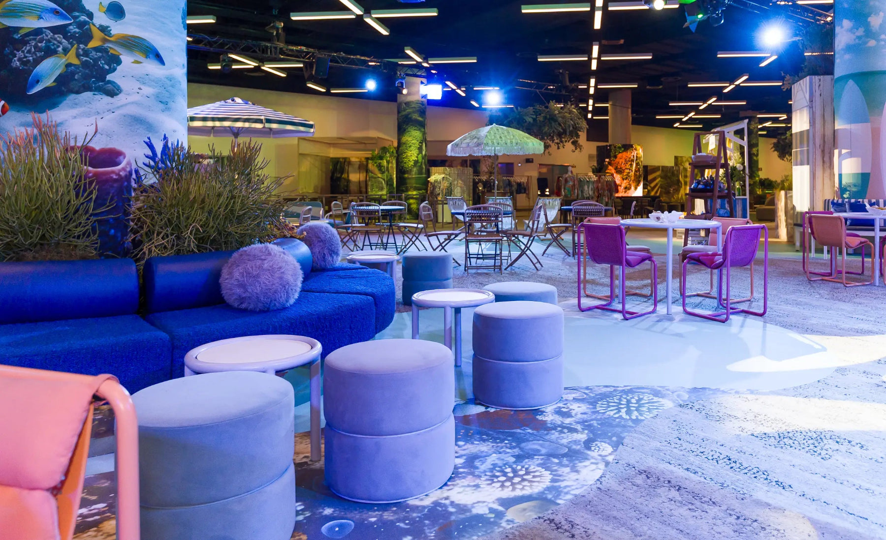 Modern expo lounge area with blue and purple furniture, decorative elements, and a mural.
