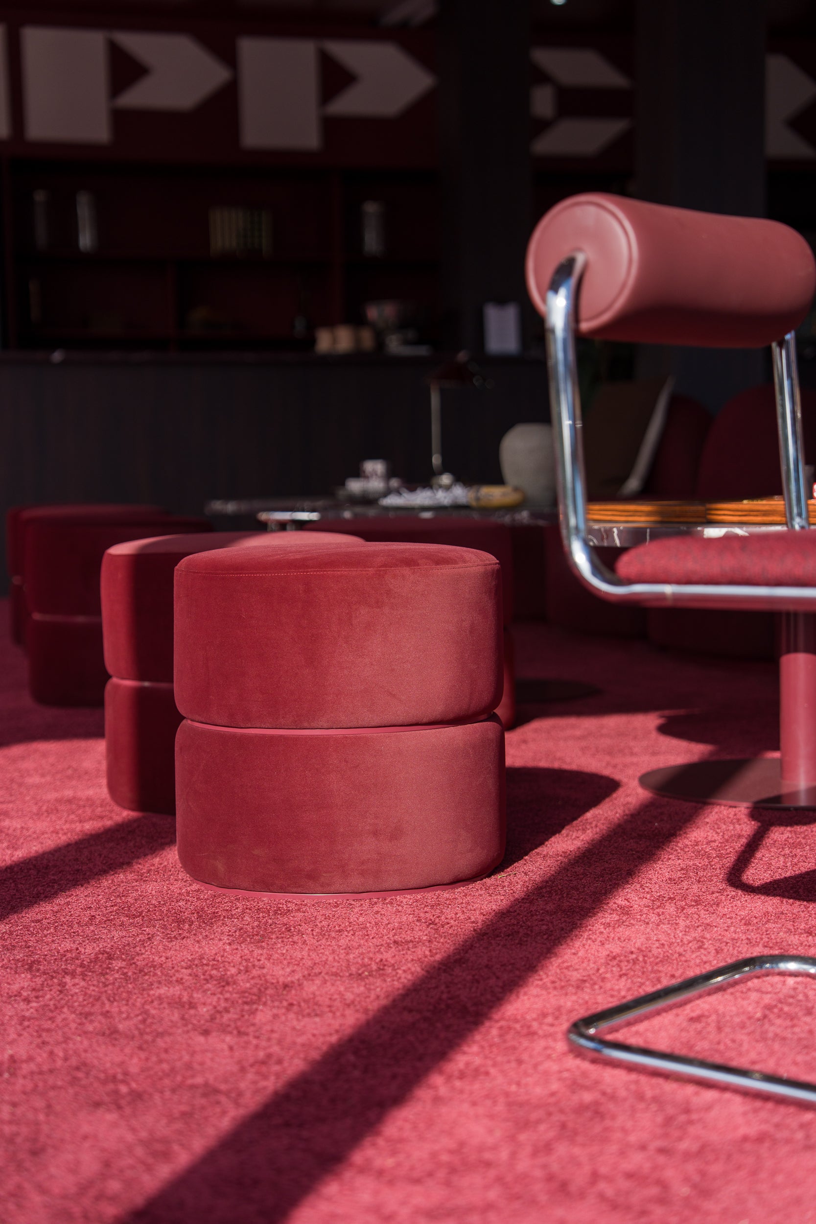 Red velvet ottomans and Zeon chair on a red carpet with blurred background