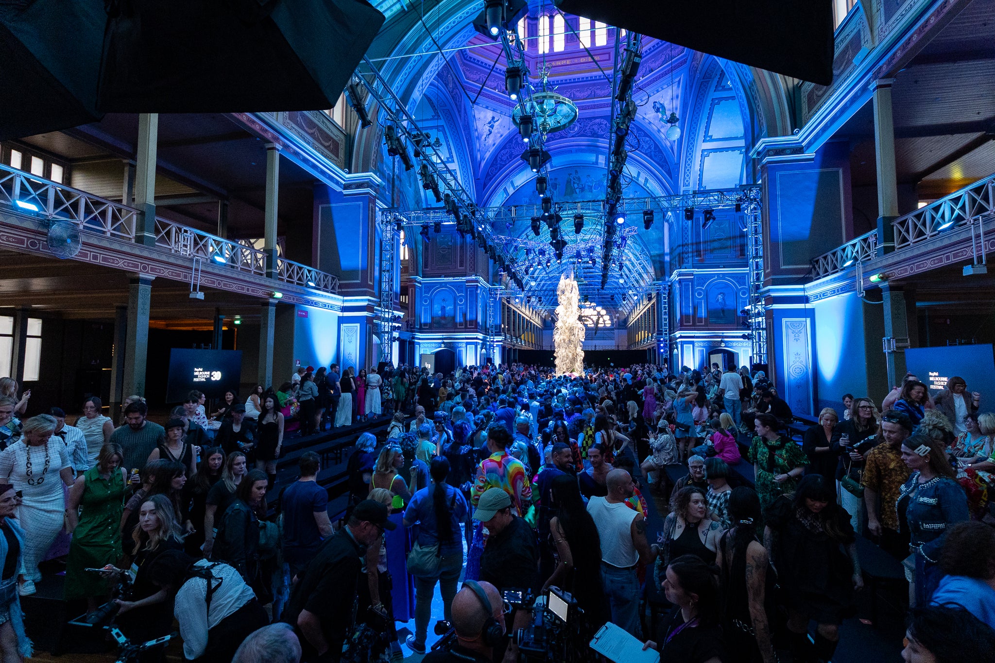 Royal Exhibition Building Melbourne featuring a runway with blue lighting and a crowd of people. For Melbourne Fashion Festival