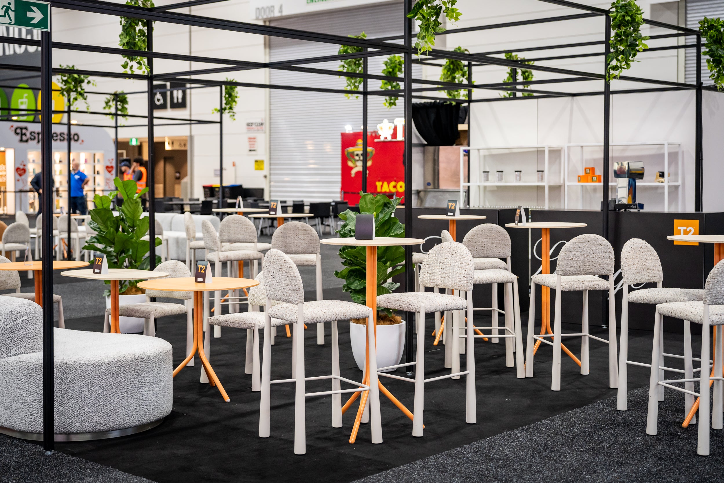 Expo seating area with white Pearl stools and orange tables.